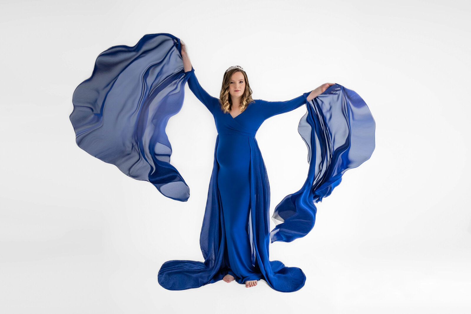 A pregnant woman in a royal blue dress with long flowing sleeves  in her Huntsville Alabama photos