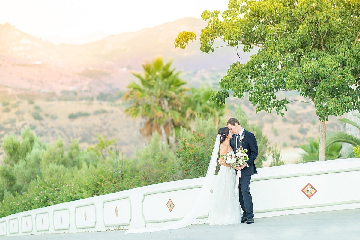 Bride and groom kissing on mountaintop at Tivoli wedding venue in Fallbrook.