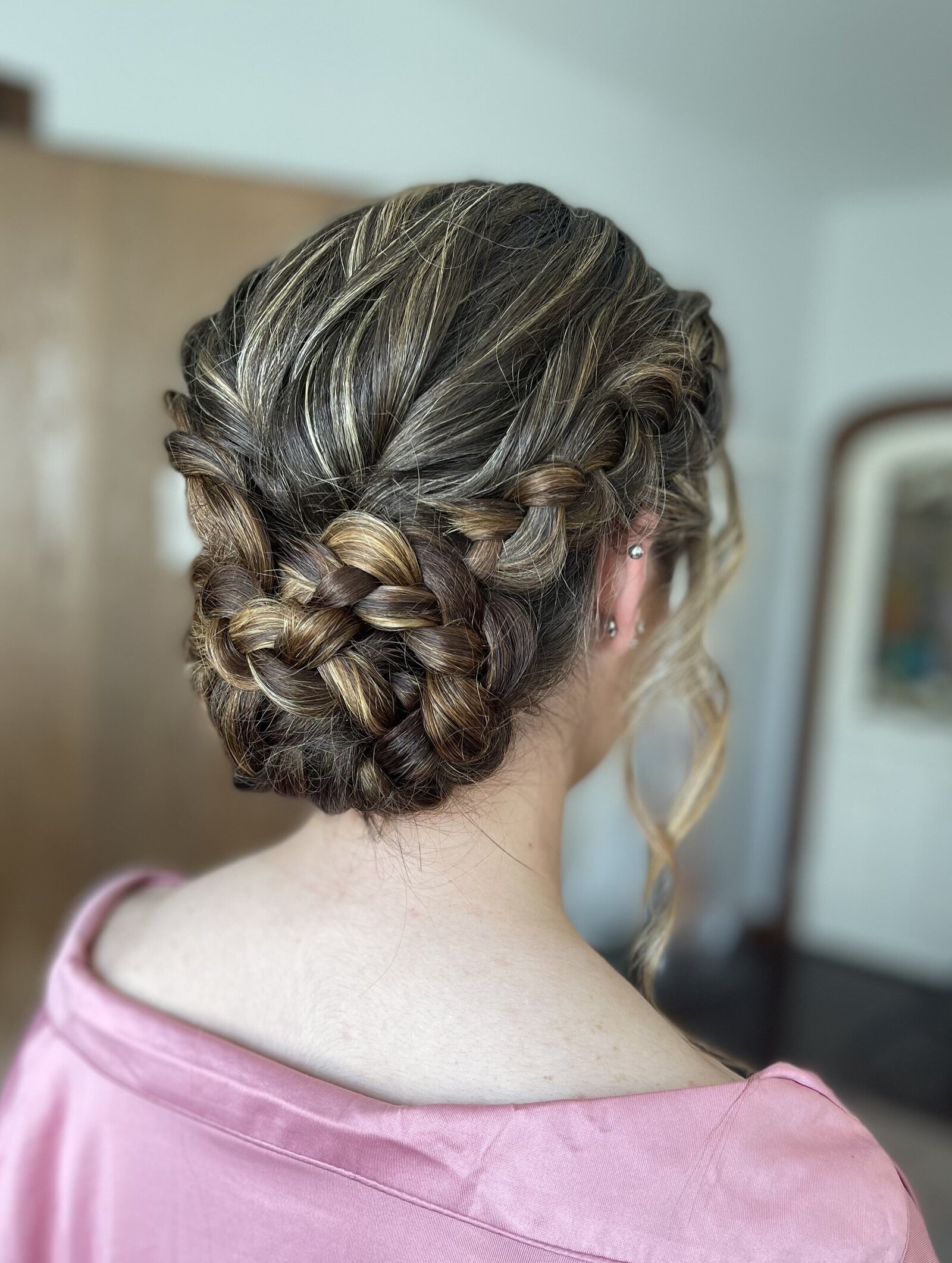 Braided low bun updo with soft texture and curls for bridesmaid bridal hair stylist Kansas City