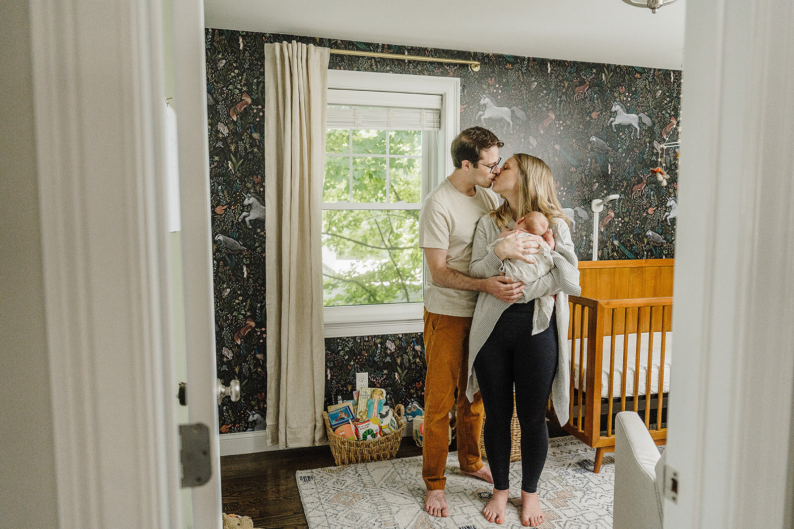 parents stand in baby girl nursery with wallpaper in boston