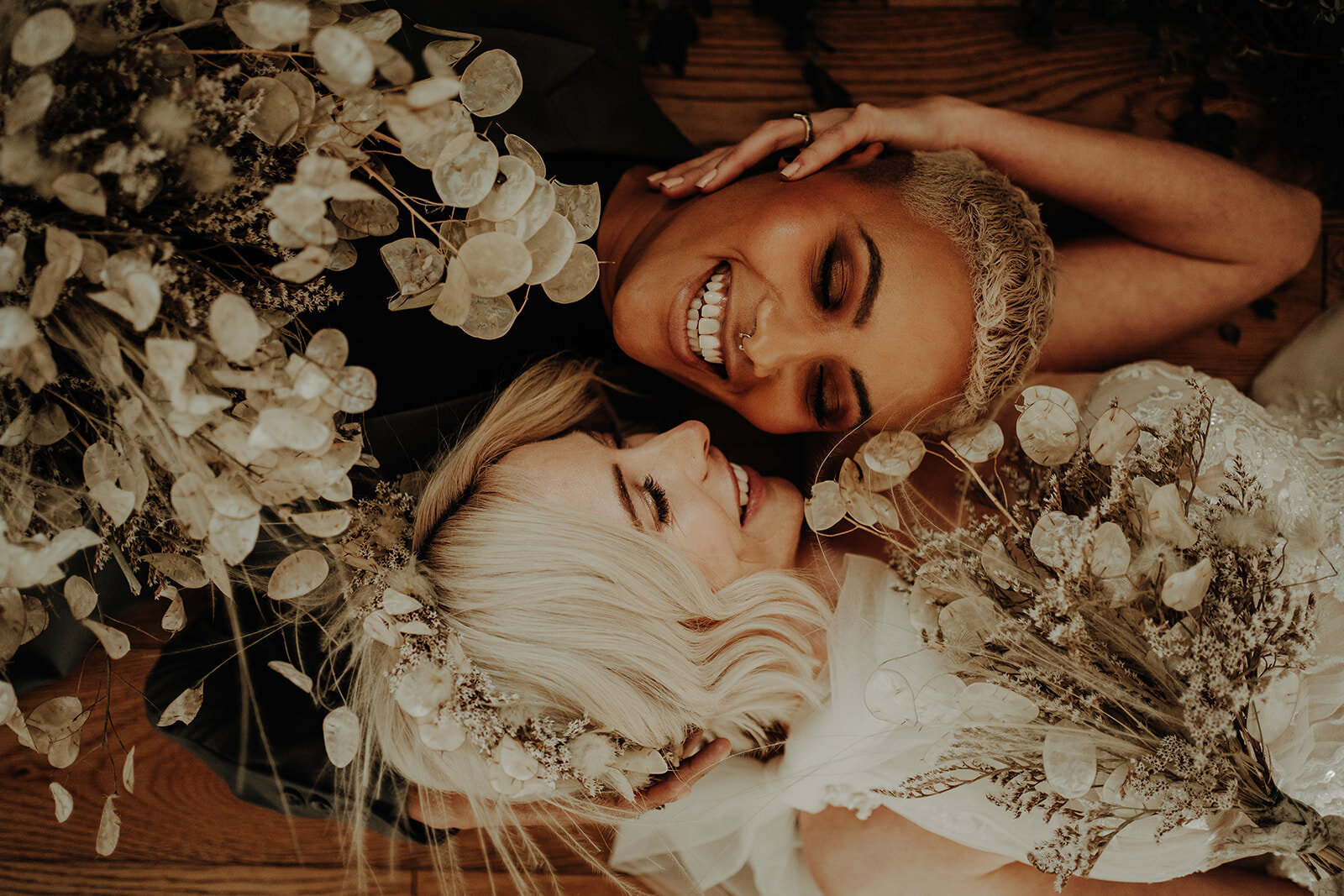 two brides lying opposite ways on floor looking lovingly into each others eyes both holding bouquets romantic alternative wedding photographer scotland