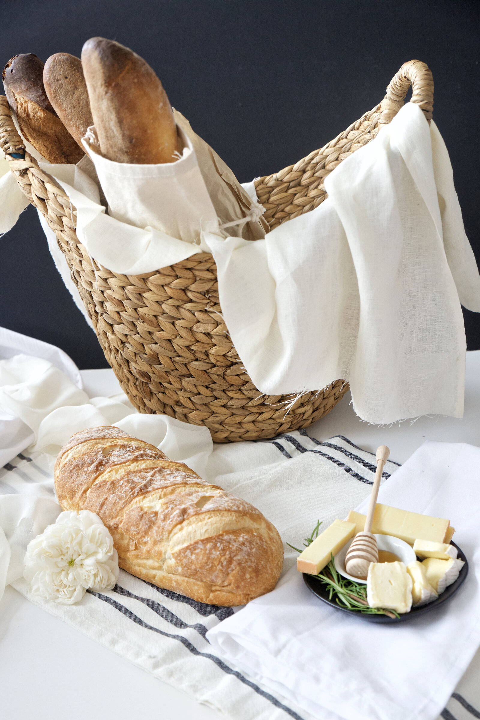 Baguettes in basket with brie and honey rustic styled food photography by San Diego branding food photographer Chelsea Loren.