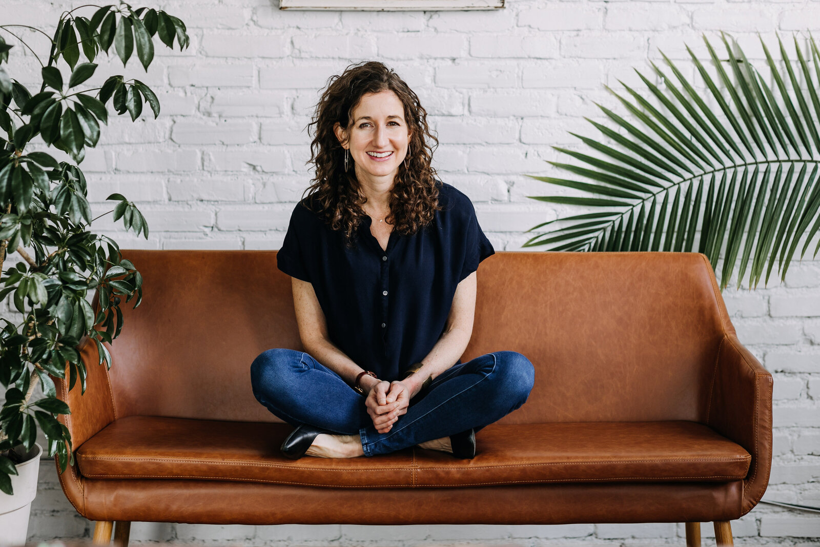 woman sitting on brown couch with plants