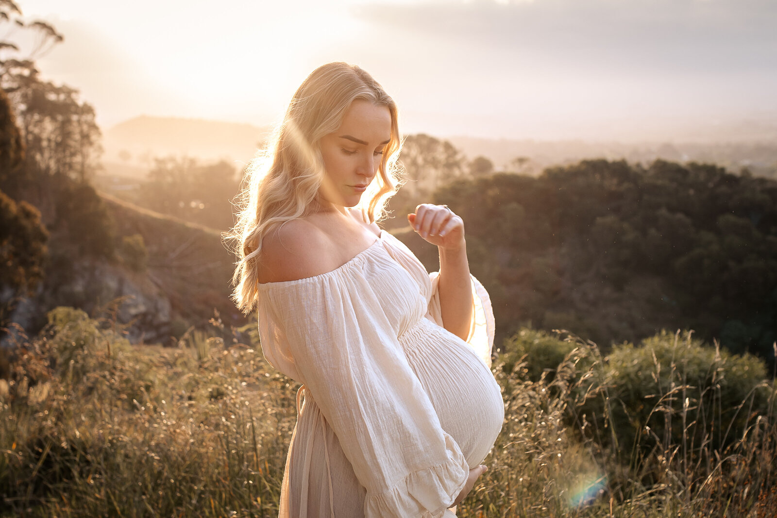 Pregnant mum standing at sunset on Te Mata Peak, dressed in flowing client wardrobe – serene maternity photography in Hawke’s Bay, Napier