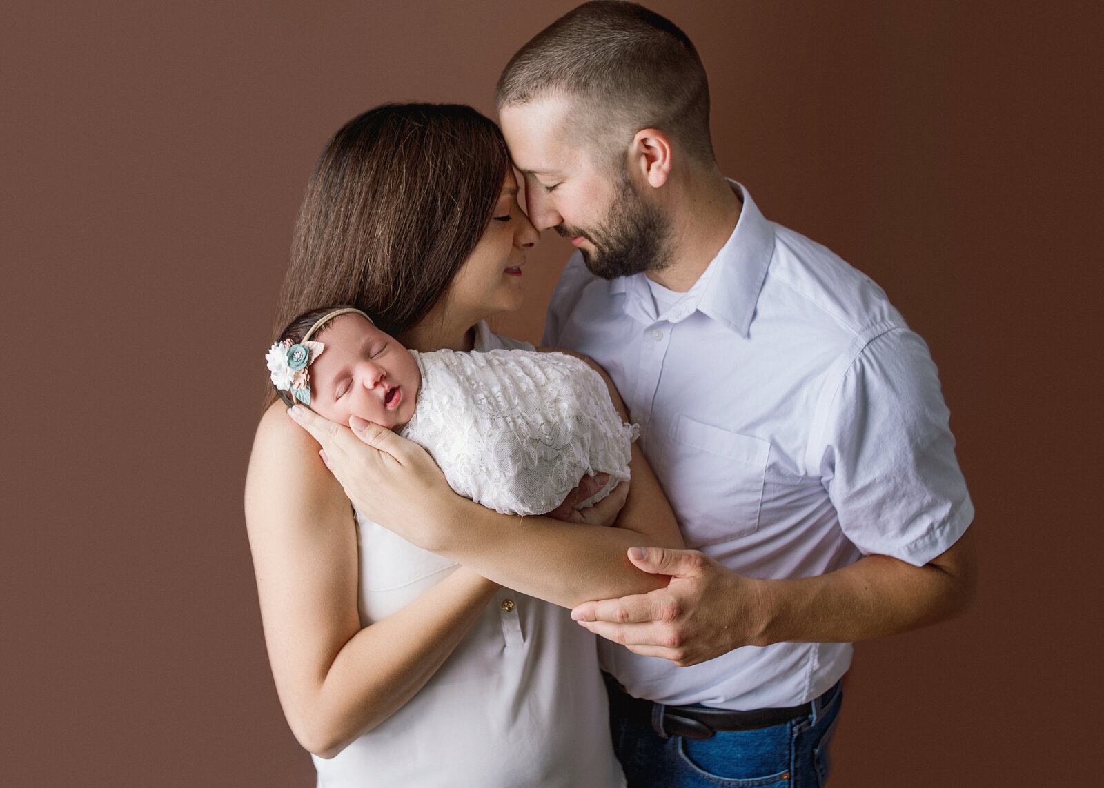 Mom and dad snuggling baby during newborn photoshoot with Nashville, TN newborn photographer