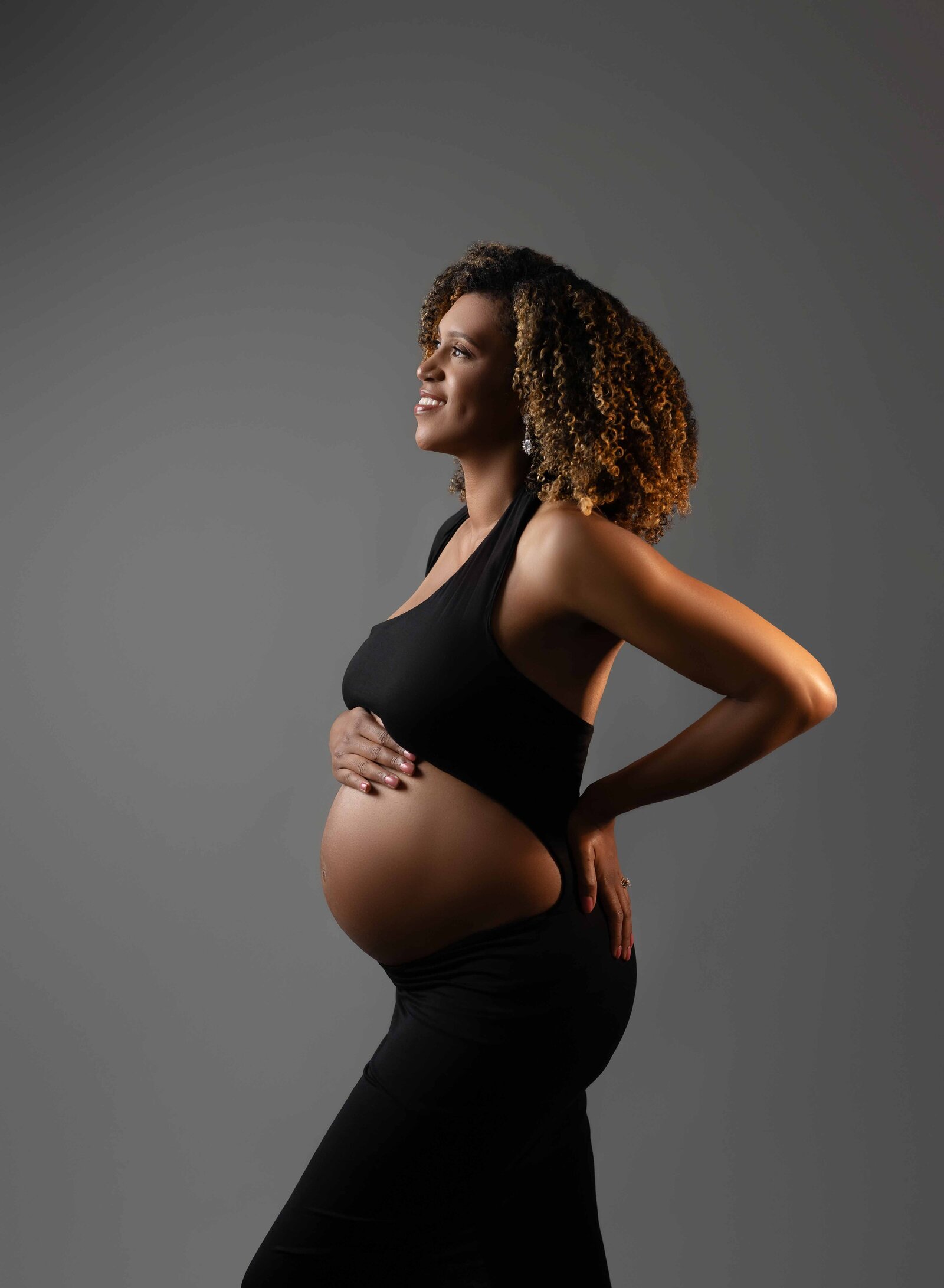 Pregnant Mom looking off and smiling with her hand on her baby bump. Photographed by Atlanta Maternity Photographer.