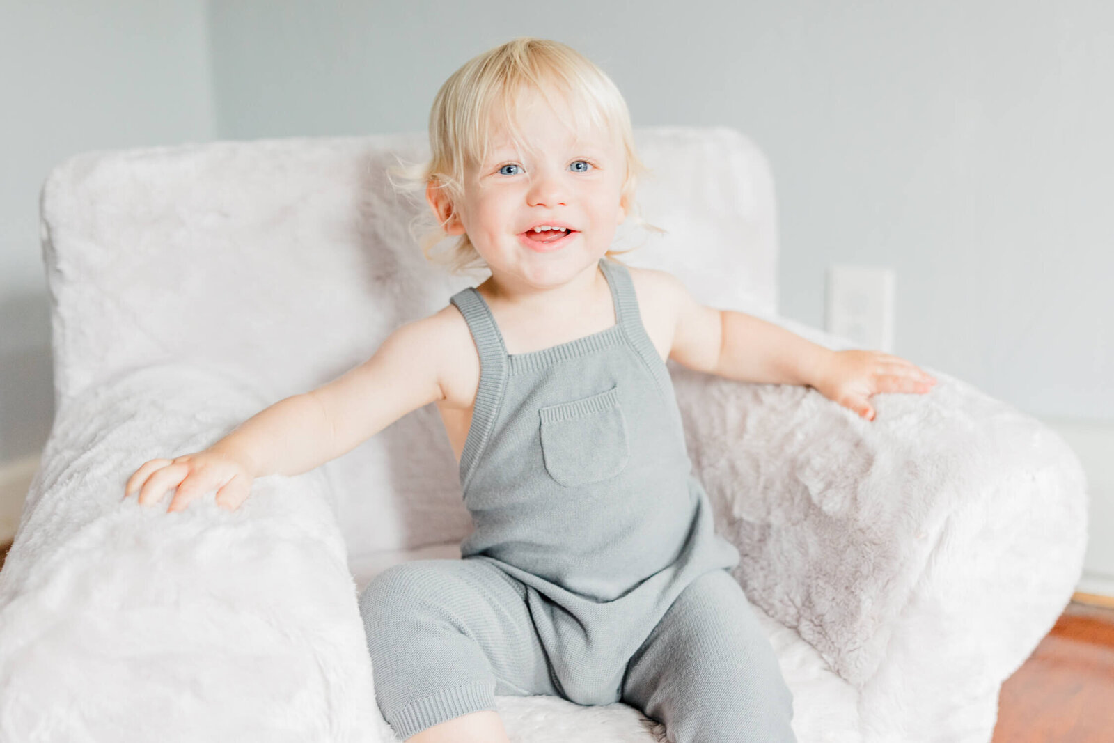 Toddler boy sits in a children's chair and smiles