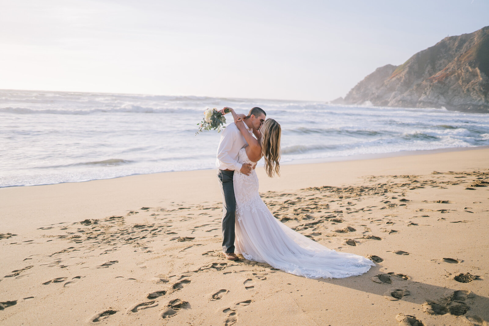 Sacramento Wedding Photographer captures bride and groom embracing on beach after wedding