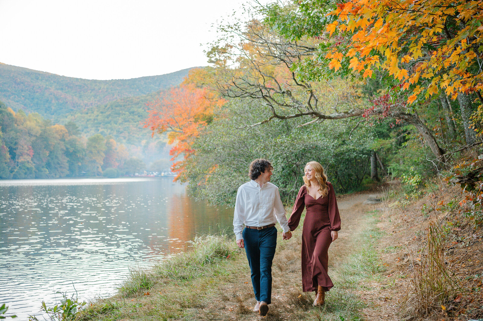 Couple holds hand while walking along lake in the North Georgia Mountains during Fall