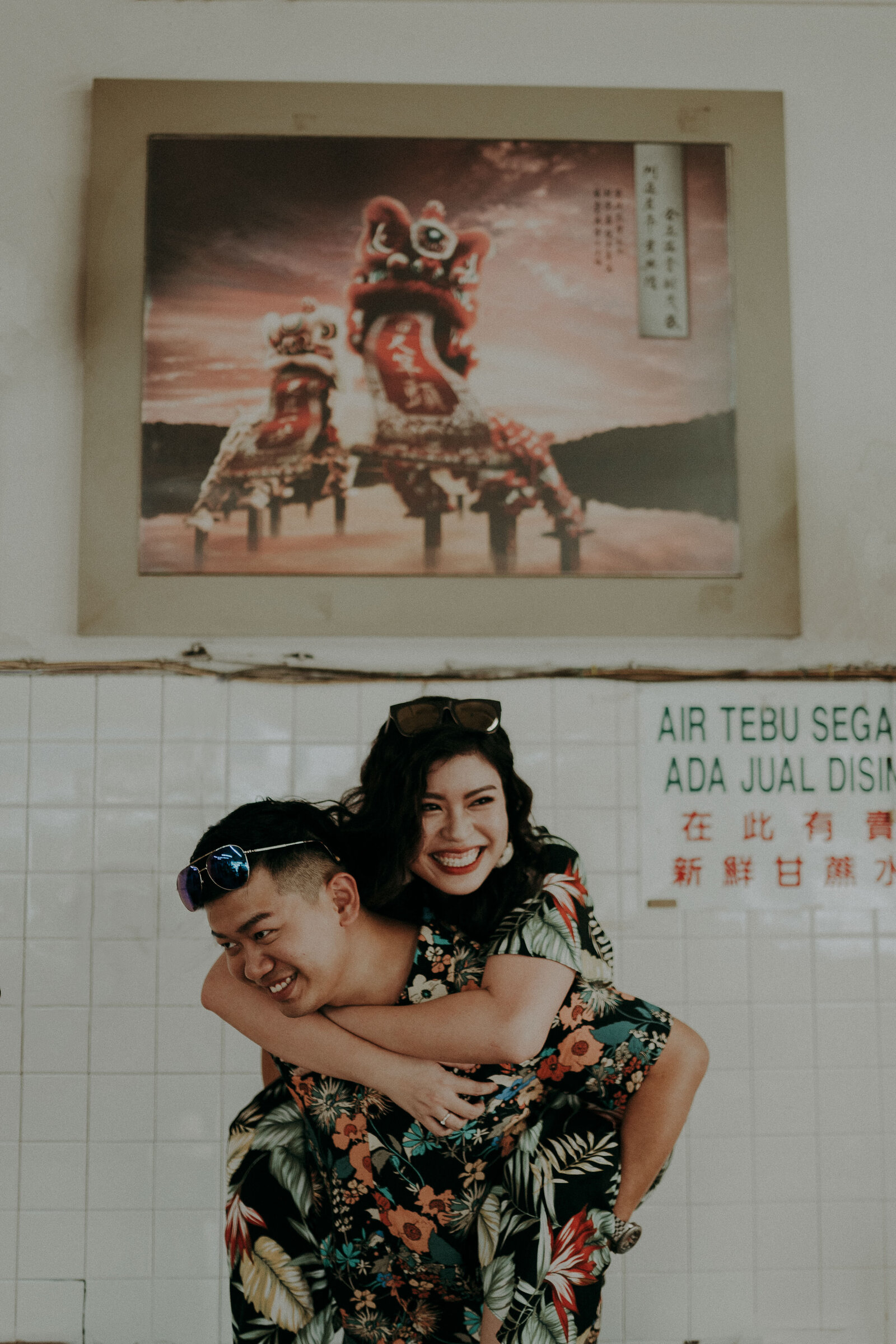 the groom carry the bride on back with a lion dance painting behind them