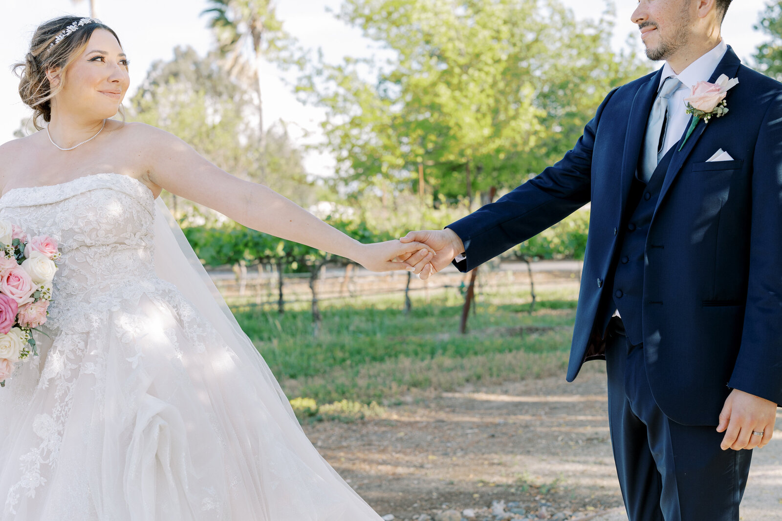 sacramento wedding photographer captures vineyard wedding photos at Wolfe Heights with bride and groom holding hands with the bride leading the groom through the vineyard as she looks back at him