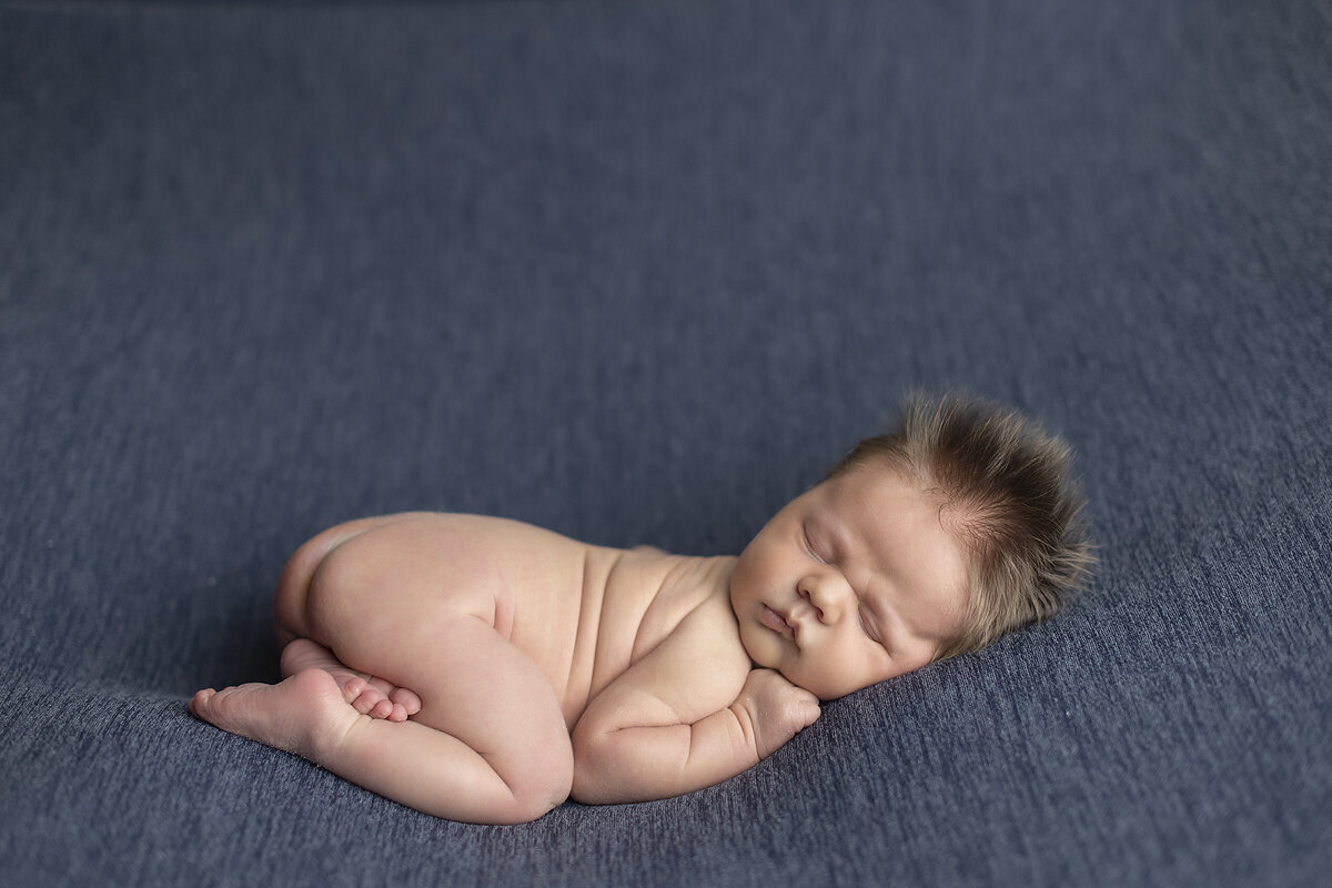 Newborn boy curled up at his Dallas newborn photoshoot.
