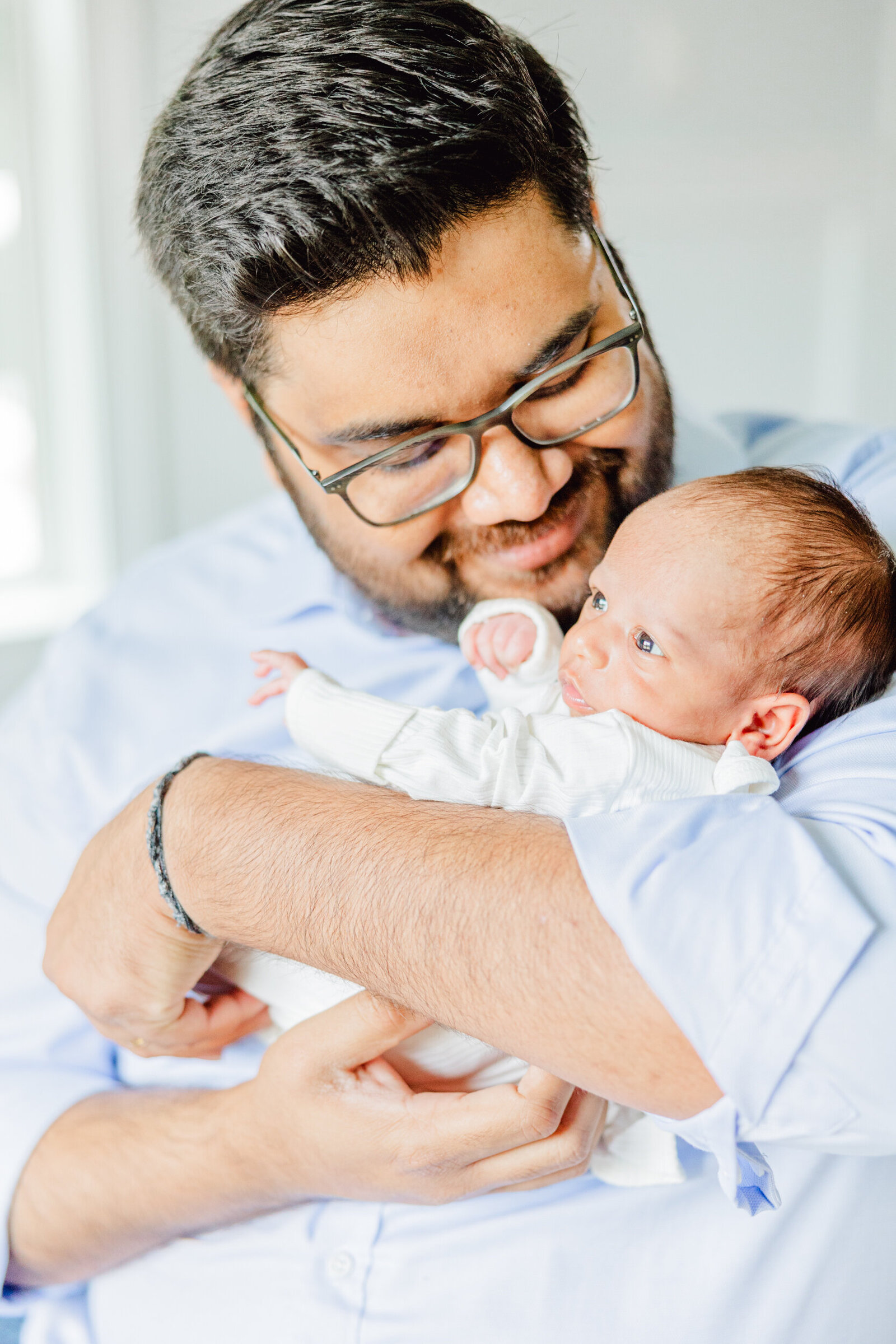 Dad holding his newborn boy close as the baby looks outward