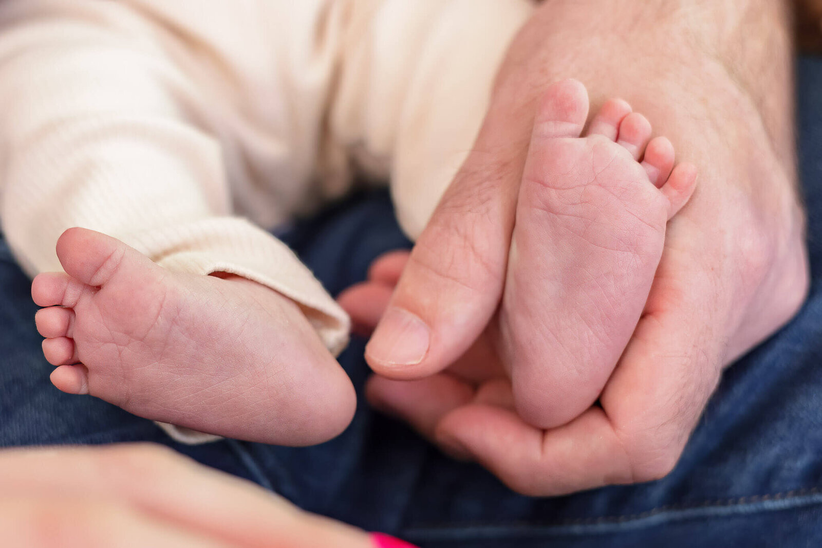 A close-up of baby girl's feet being held by dad's hand.