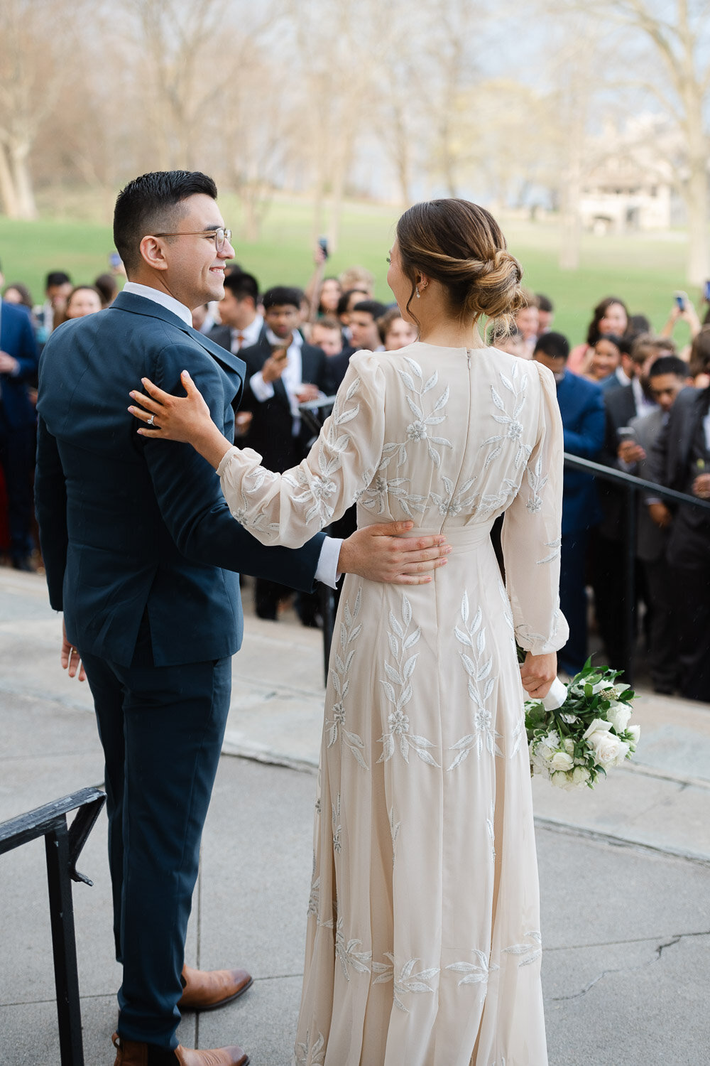 bride and groom from behind on patio with guests in background