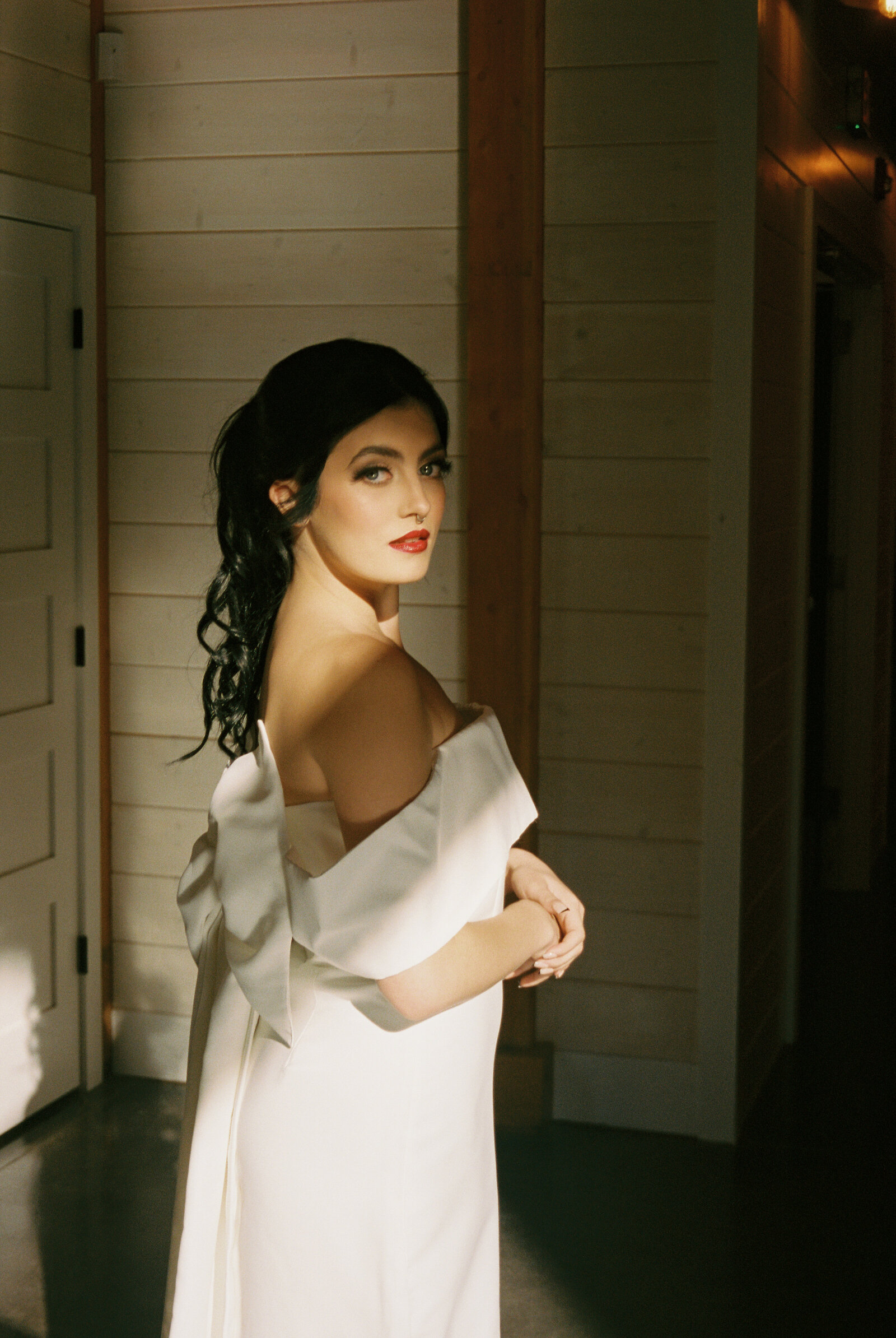 A moody film photo of a bride in a modern short reception dress at an alternative wedding photoshoot.