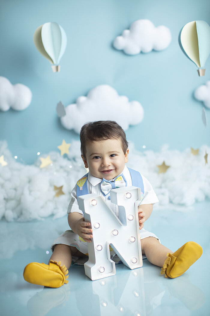 Baby boy holding letter N at his first birthday photoshoot.