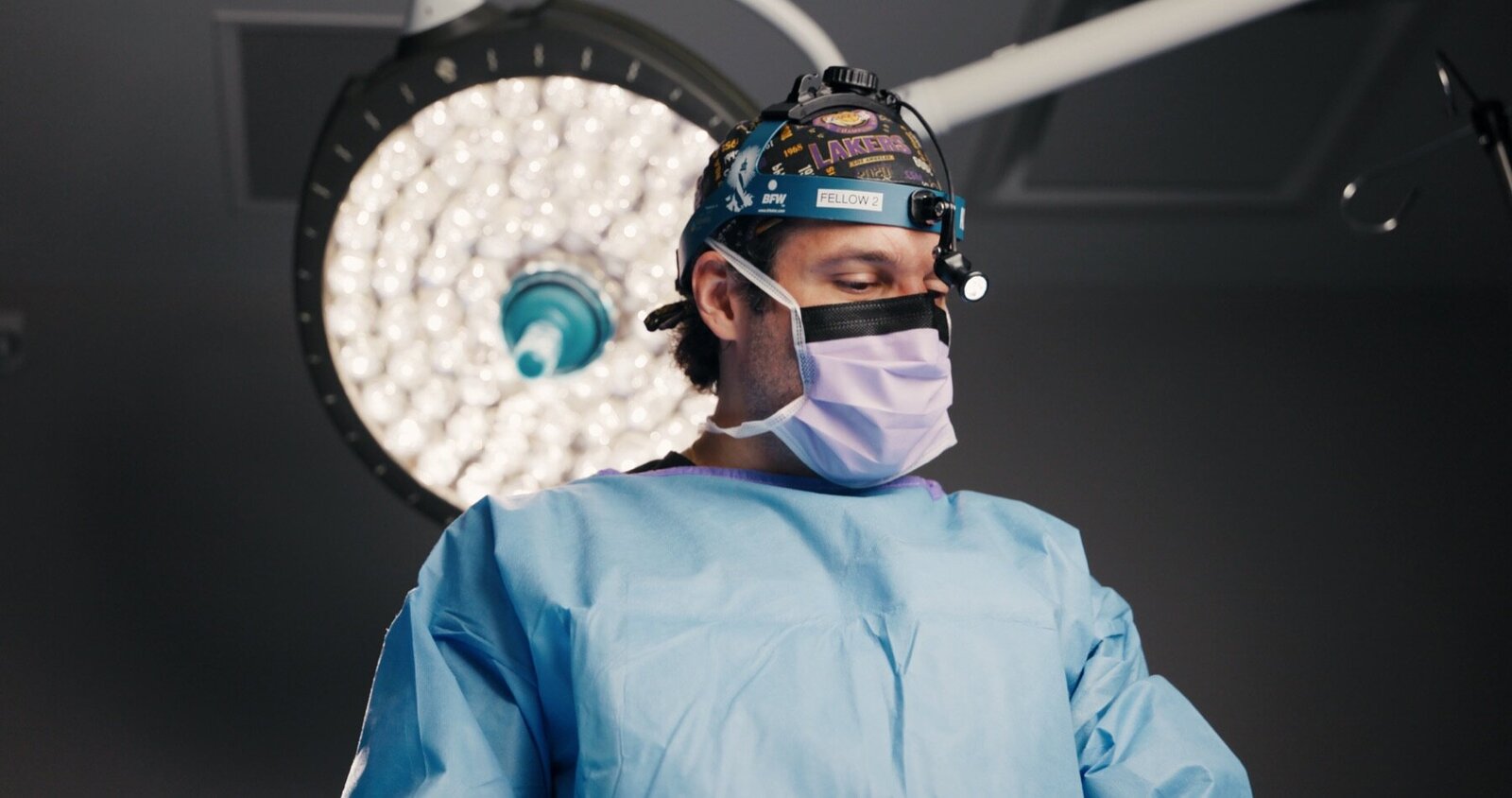 Surgeon in a gown and mask under an operating room light