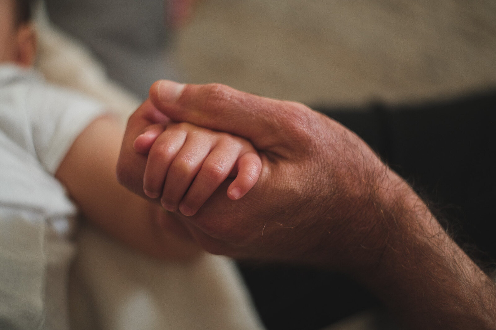 closeup of a father's hand holding his child's hand