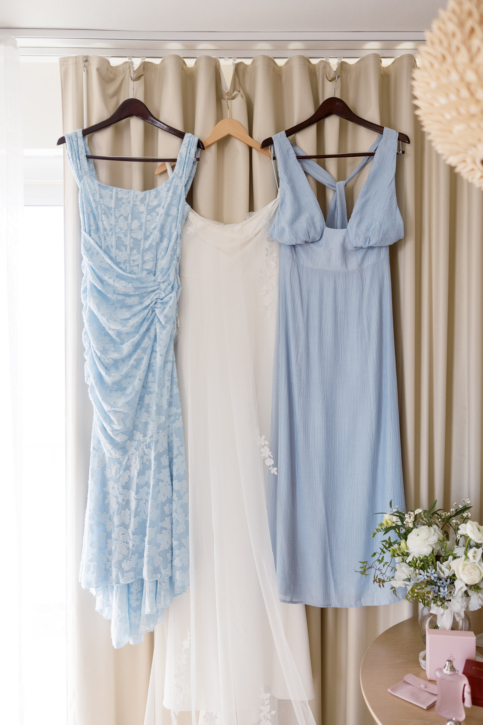 Blue bridesmaid dresses hanging next to brides dress in hawaii