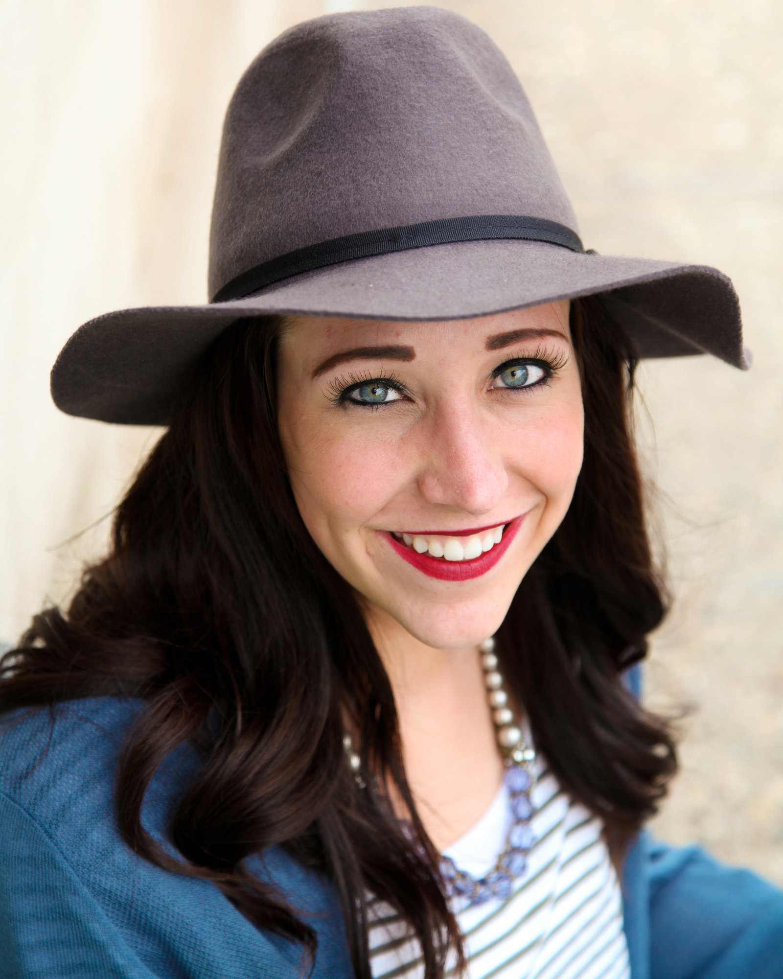 Woman in hat with red lipstick smiling at camea.