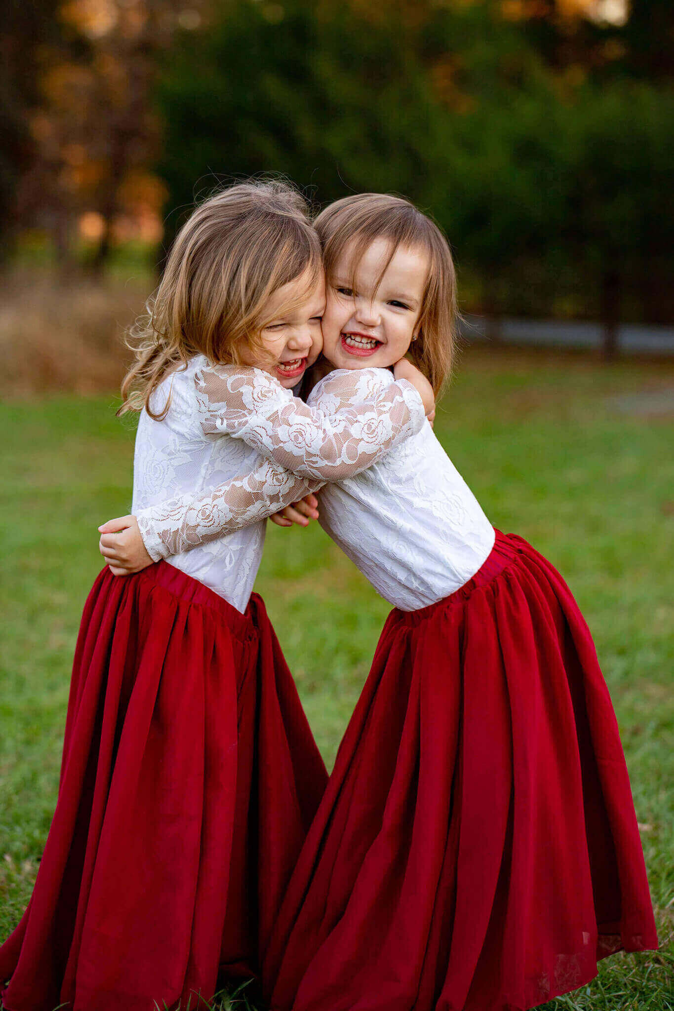 Twin sisters in white tops and red skirts hugging.