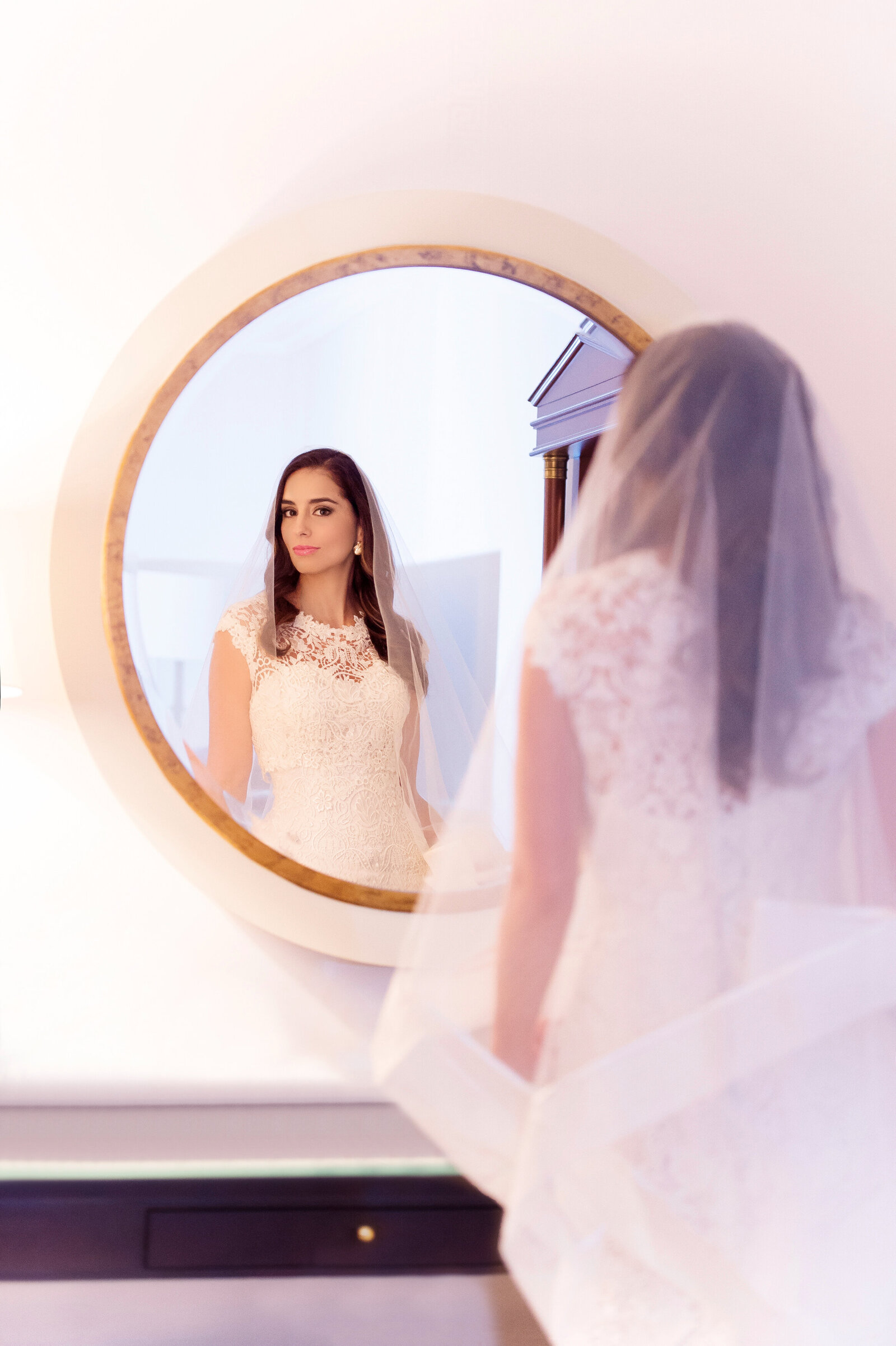 Bride looking into round mirror