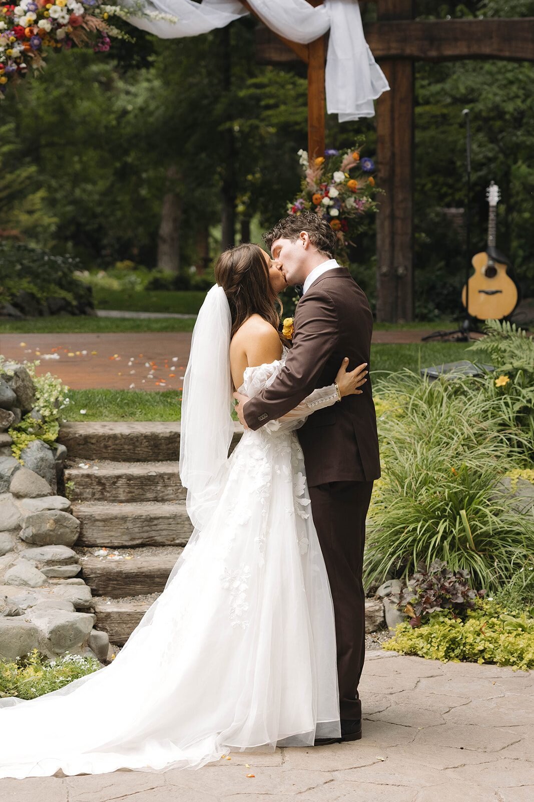 First kiss at the outdoor ceremony under a wooden arbor