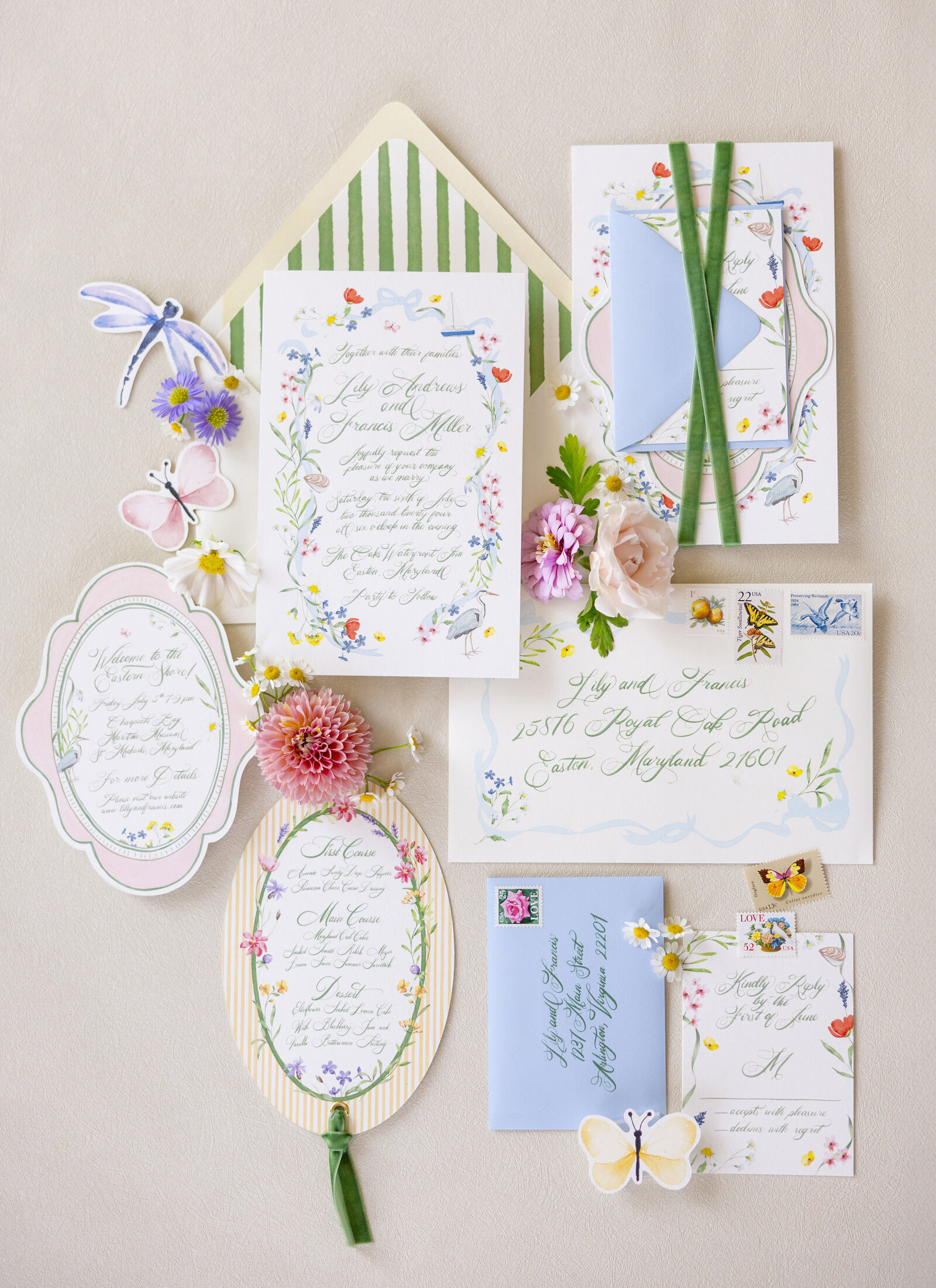 Elegant floral-themed wedding invitation suite with cards, envelopes, and decorative elements like flowers and butterflies. Includes handwritten text, pastel colors, and vintage stamps, arranged on a soft, textured surface.