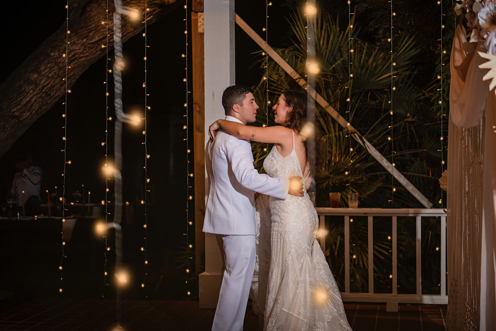 A romantic moment as the bride and groom kiss under a canopy of string lights, captured during a Texas Hill Country wedding by CMH Studios.