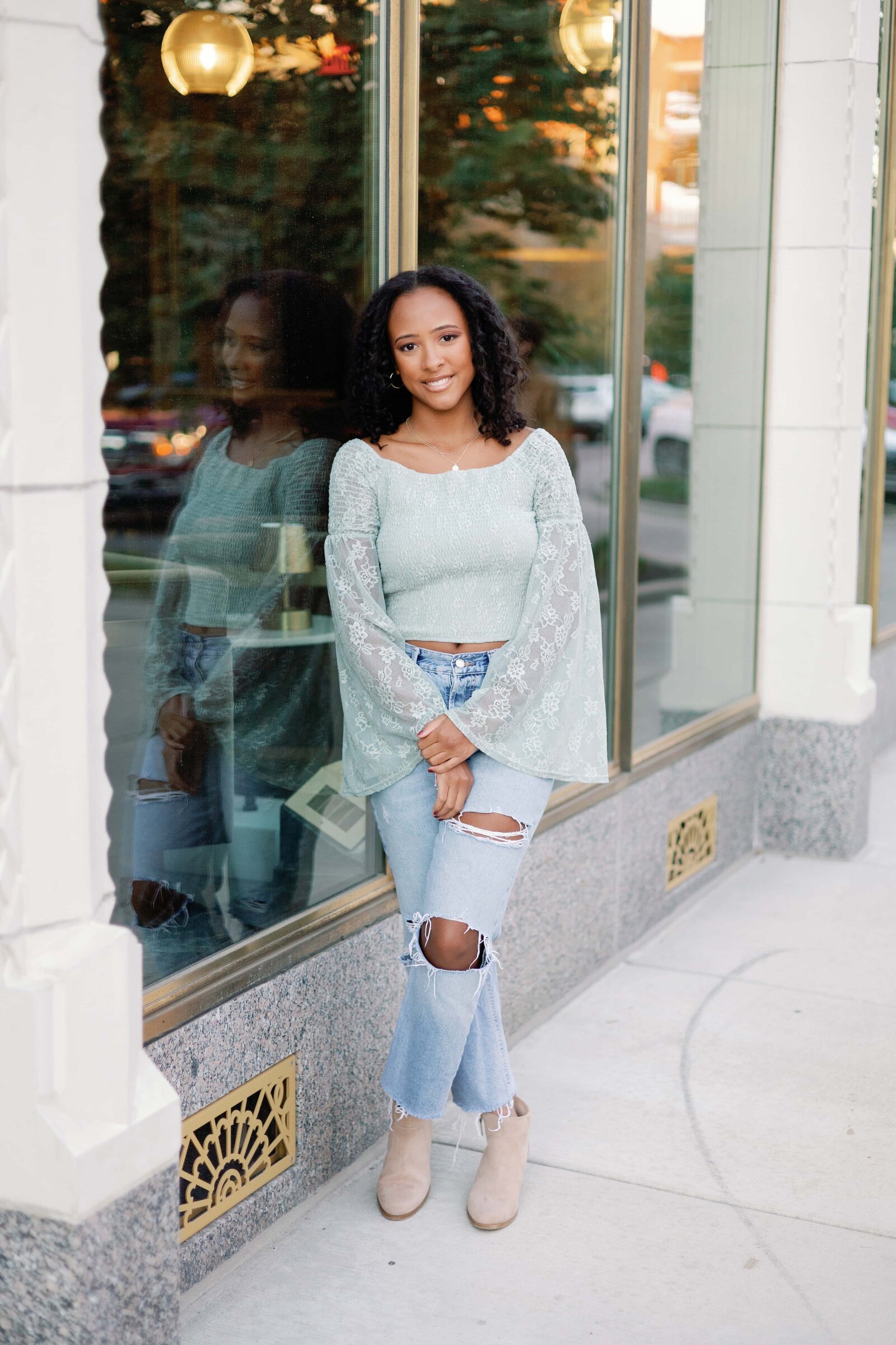 Senior girl posing leaning against glass window at Bottleworks District