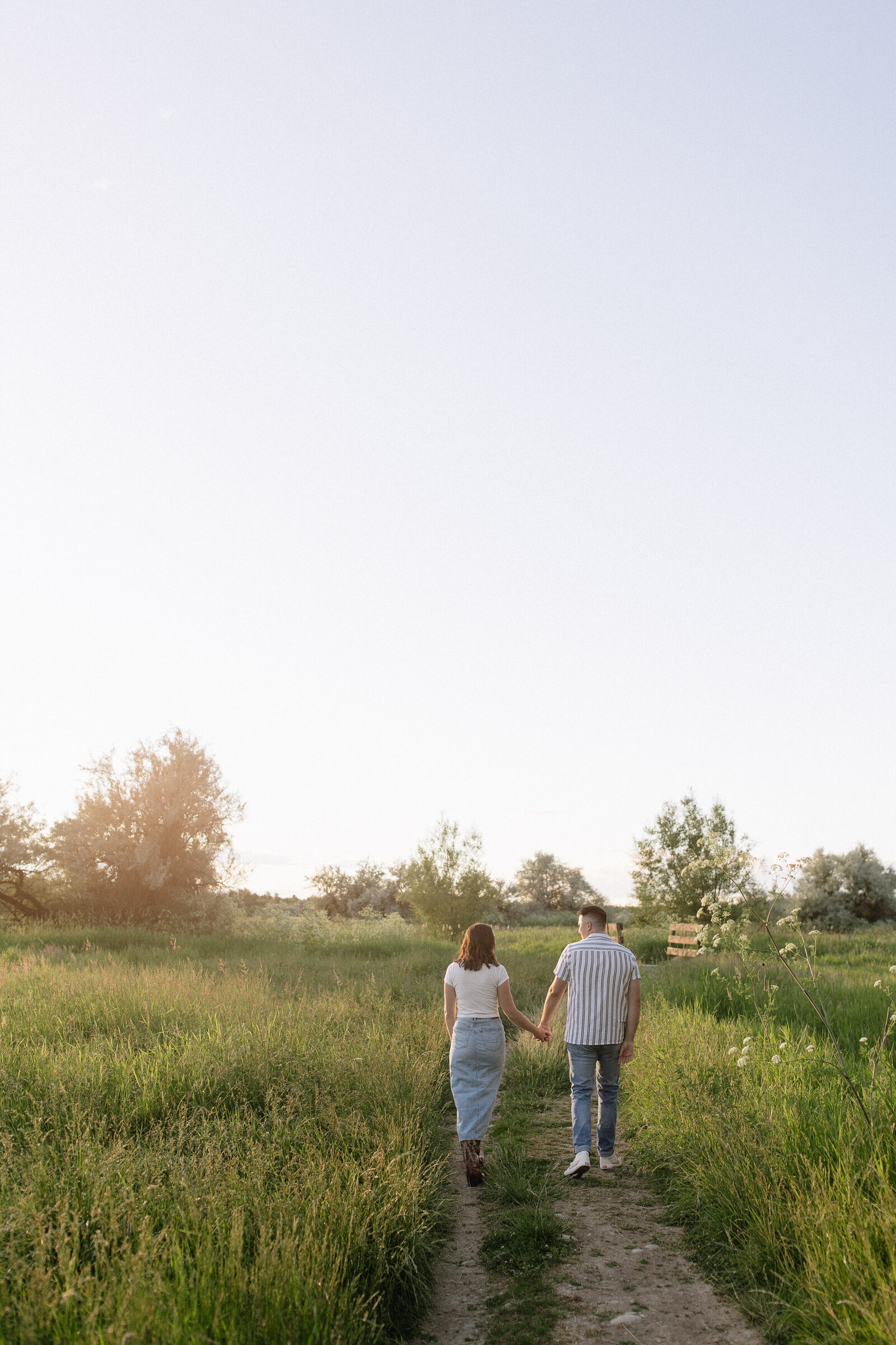 Couple walking hand-in-hand through open meadow in rural Idaho