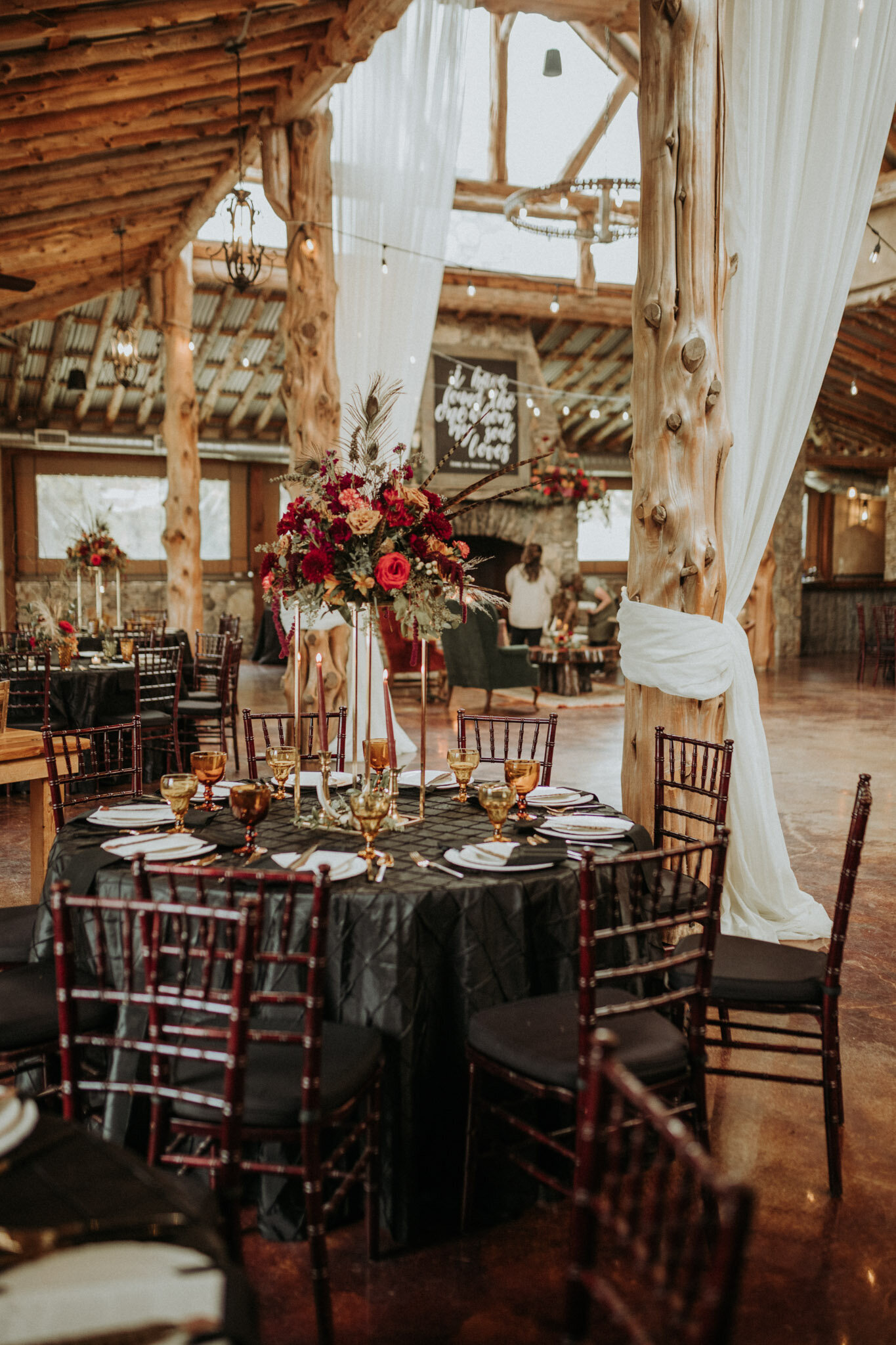 rustic western table at wedding with tall flowers, tablecloths, china, amber glasses