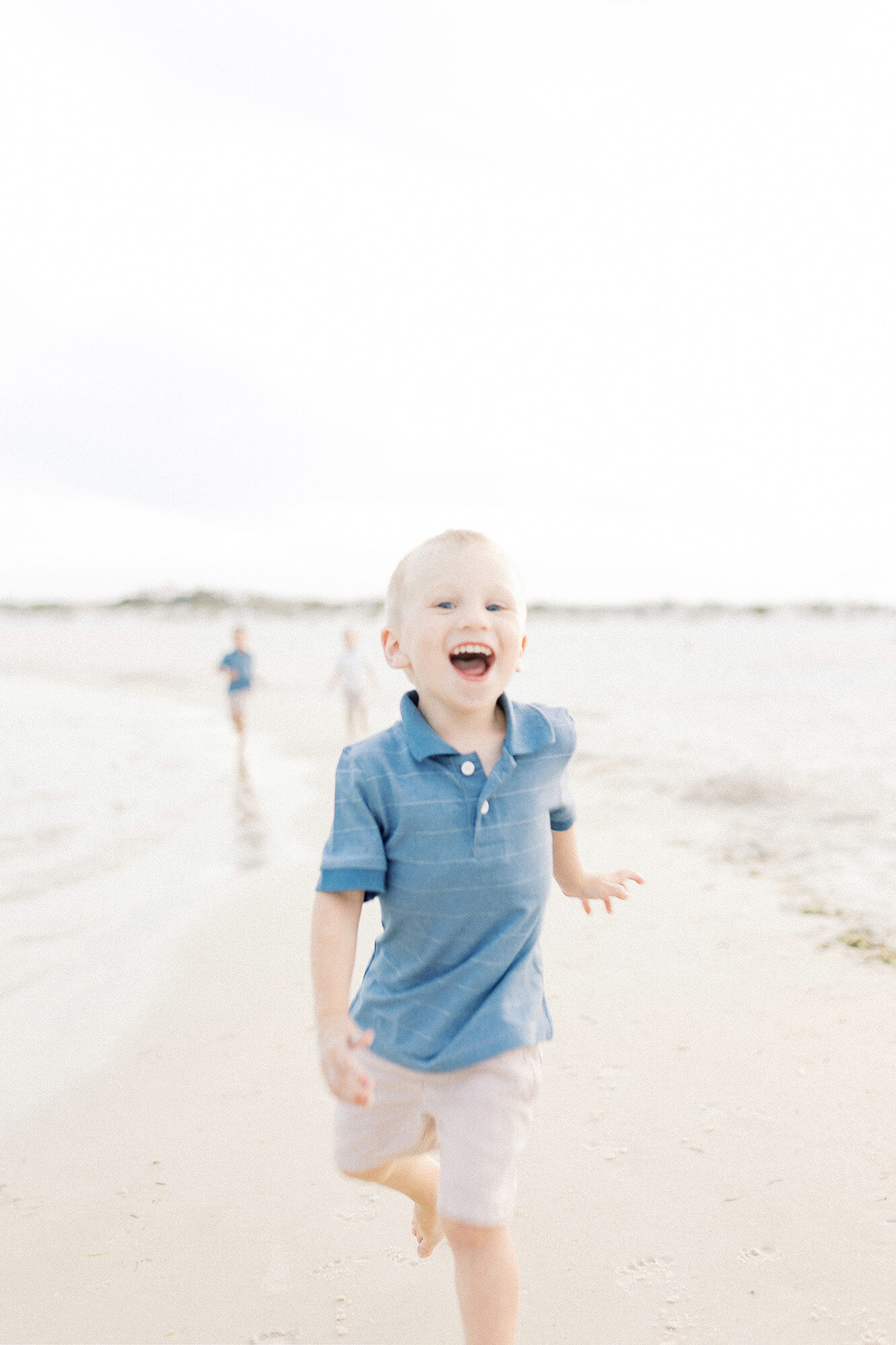 Smiling young boy running on the beach during a Grand Forks family photography session with Chelsea Nichole Photography