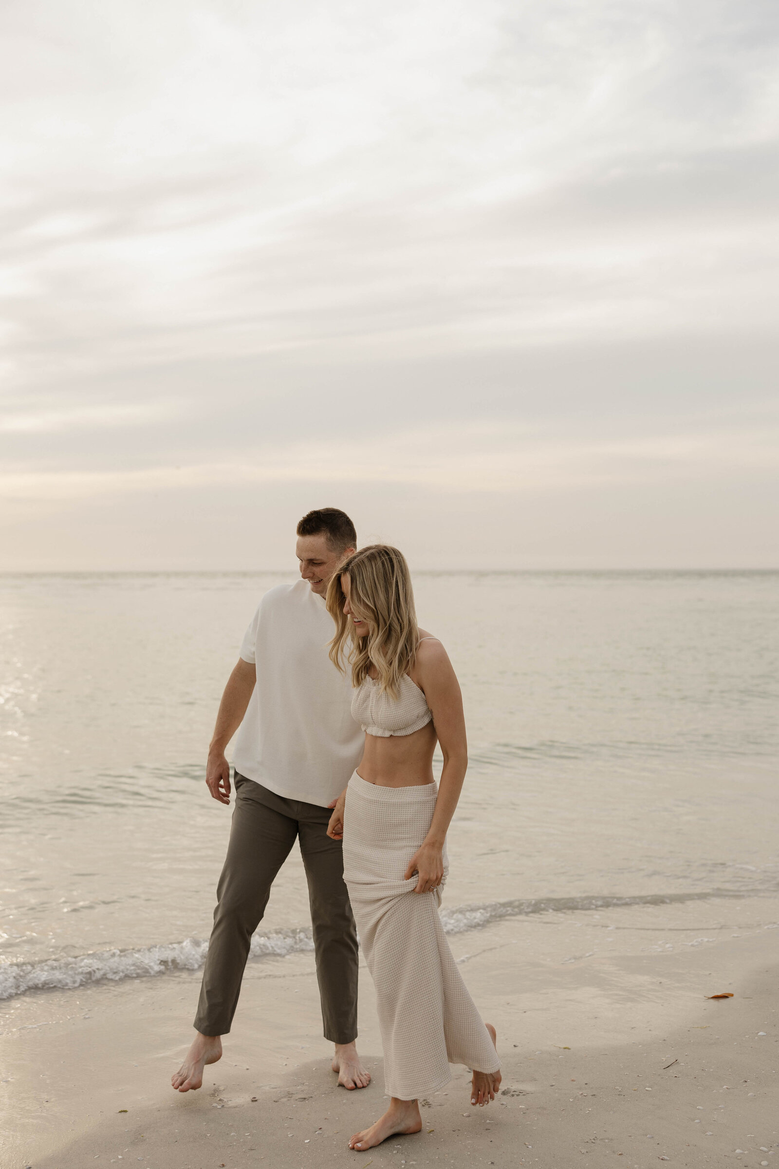 Photo of a couple in love, walking during a photography session on a beach at sunset.