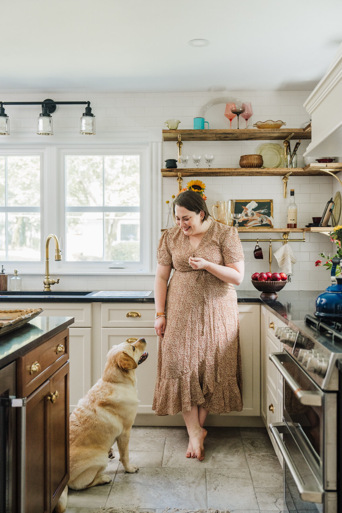 woman in a dress looks at dog in her antique styled kitchen