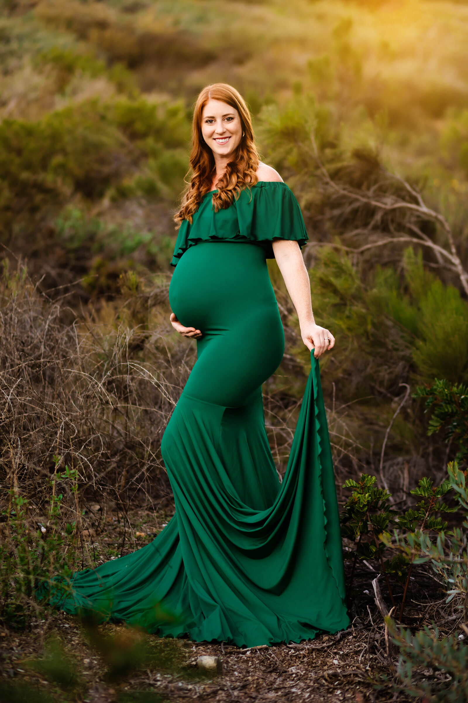 Maternity Photographer, a pregnant woman stands smiling in her gown in the wild