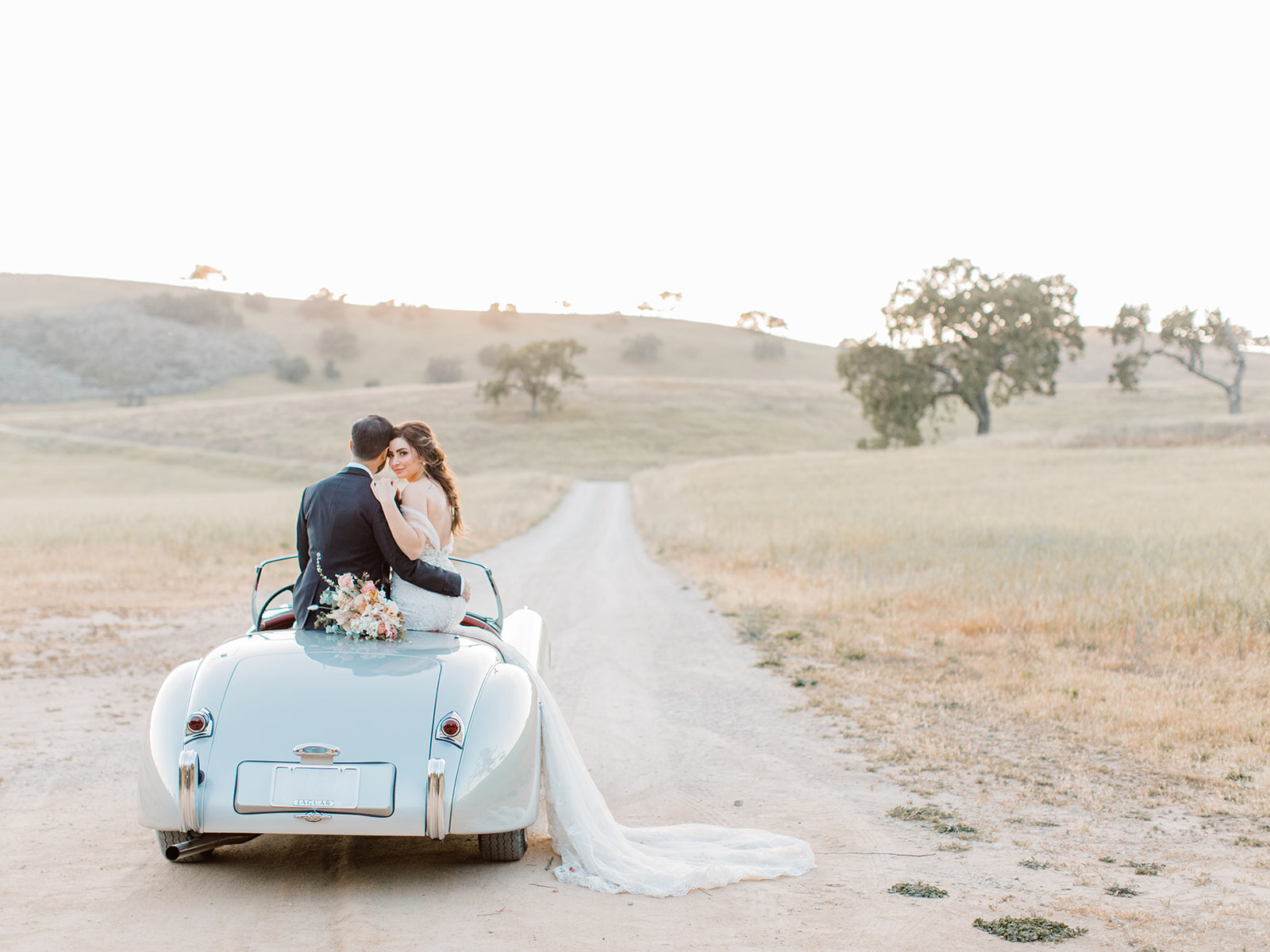 bride and groom sitting on a classic car