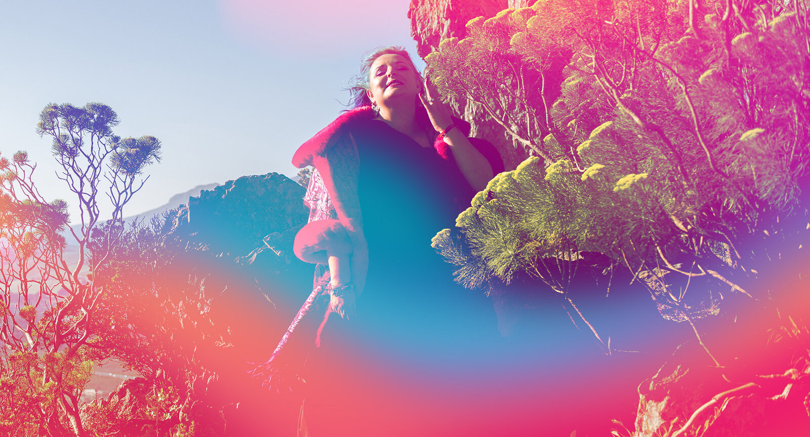 Woman on a mountain in vibrant colours, fiercely claiming her freedom.