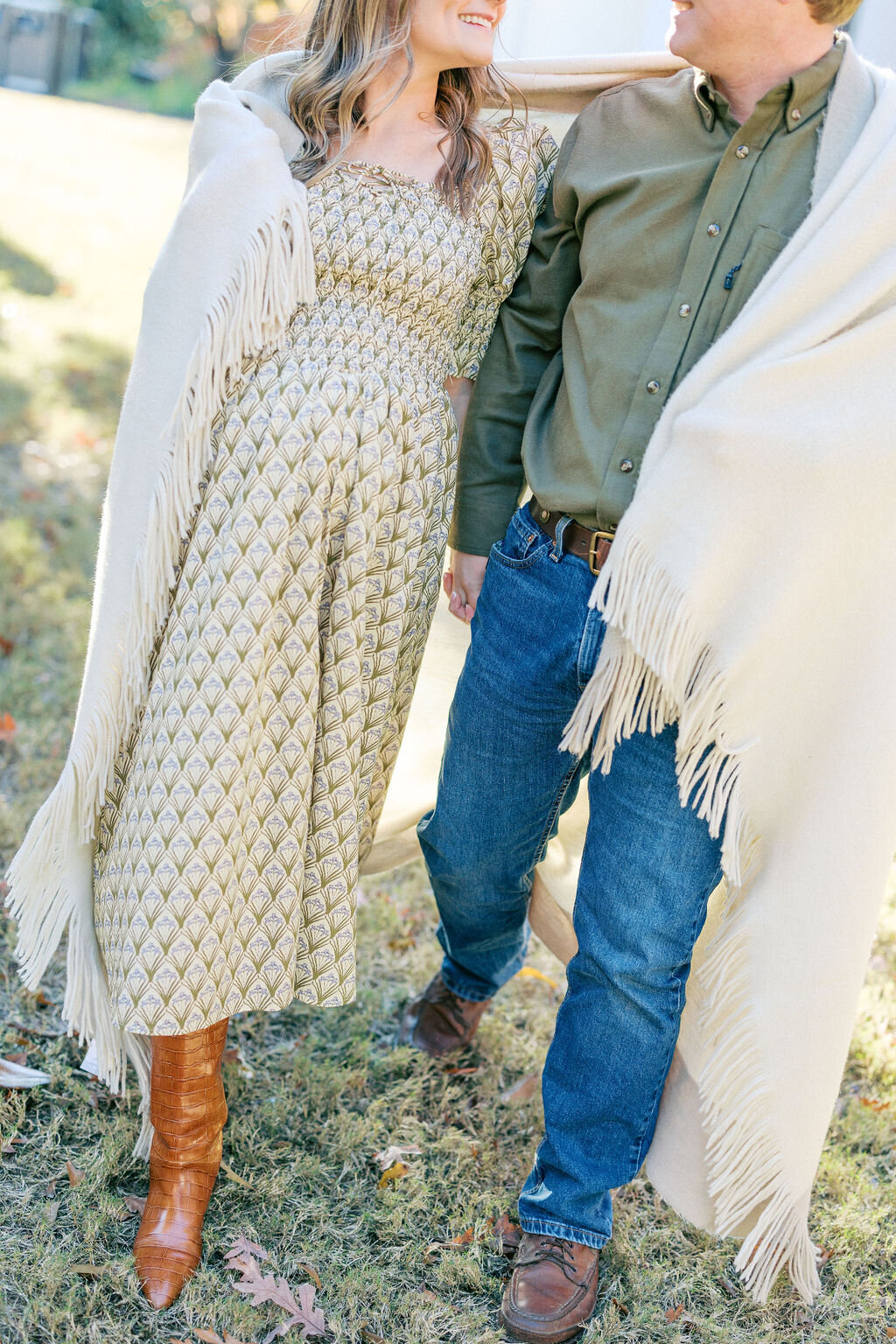 Husband and wife with blanket draped around shoulders walk carrying baby bump