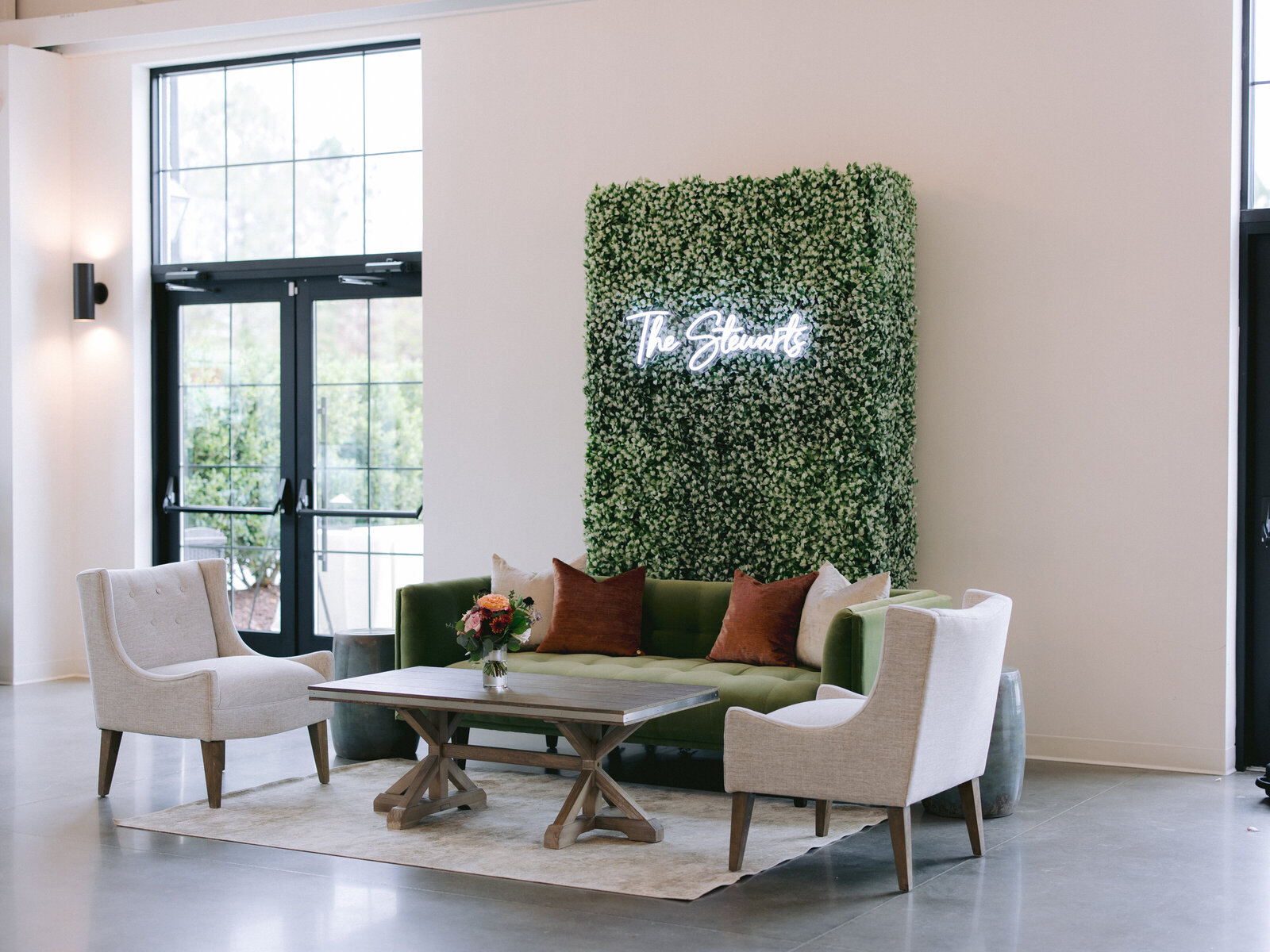 lounge set in front of boxwood wall with neon sign