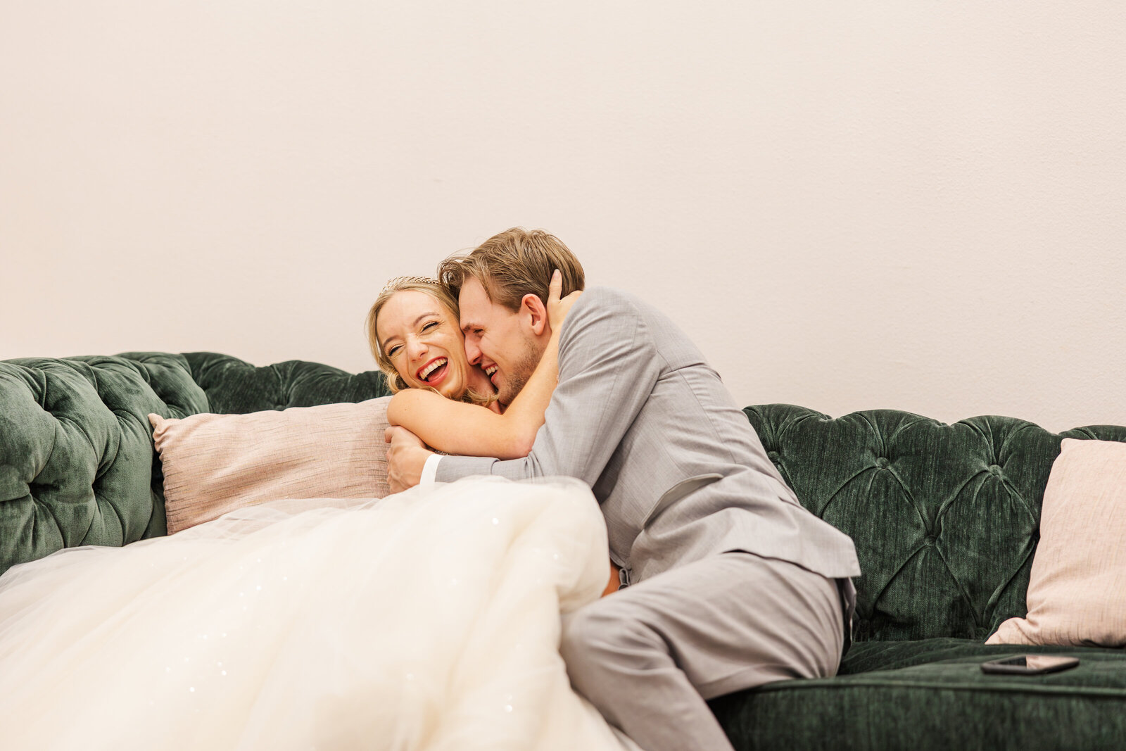 Bride-and-groom-sitting-on-sofa-holding-each-other