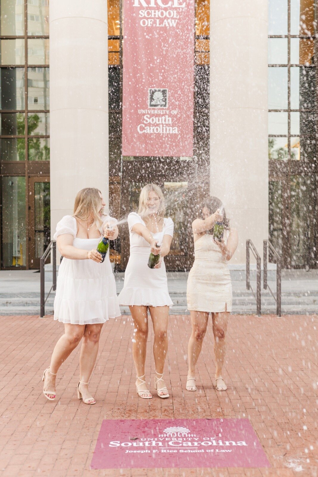 Friends popping champagne bottles after graduation