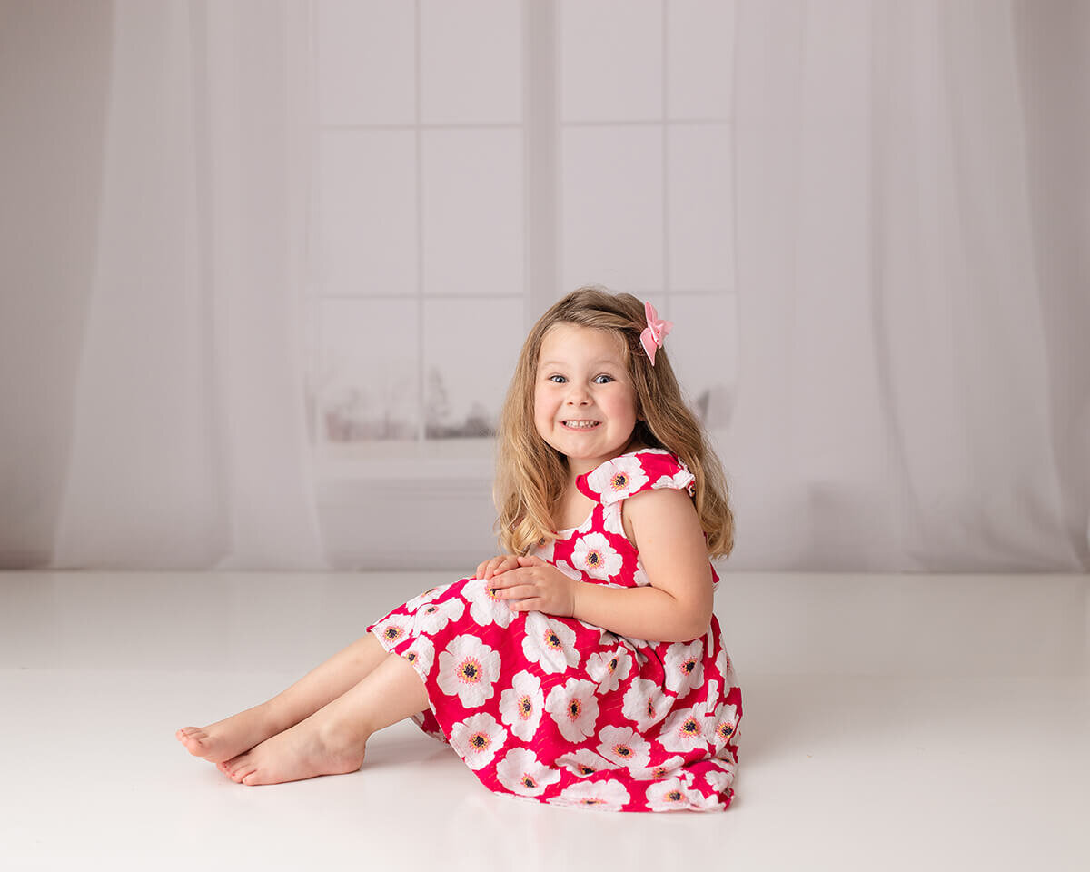 Little girl smiling on the floor with hands on knees, Child photographers Ames