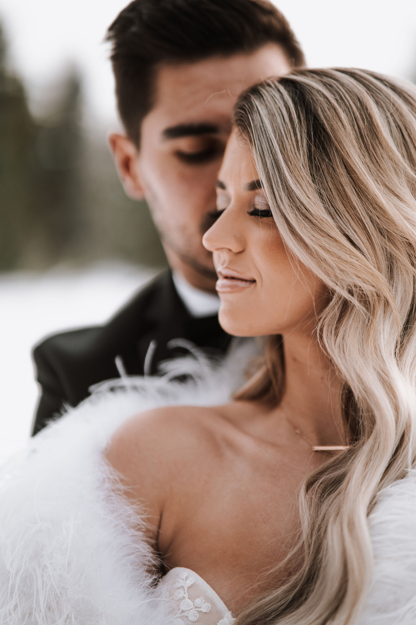 Bride and Groom are embracing while surrounded by white snow captured by Idaho Falls Wedding Photographer