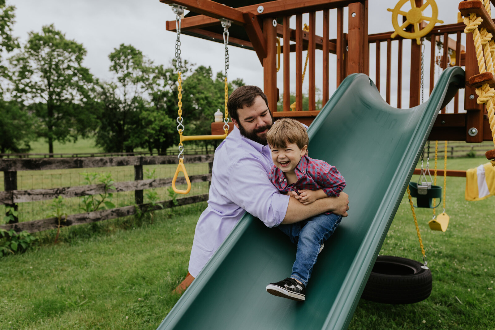 A father and son play on a green slide