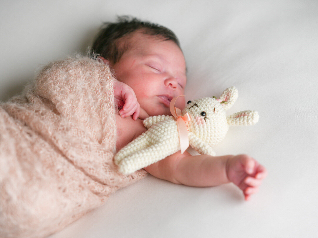 newborn photo of little girl sleeping with her crochet bunny rattle