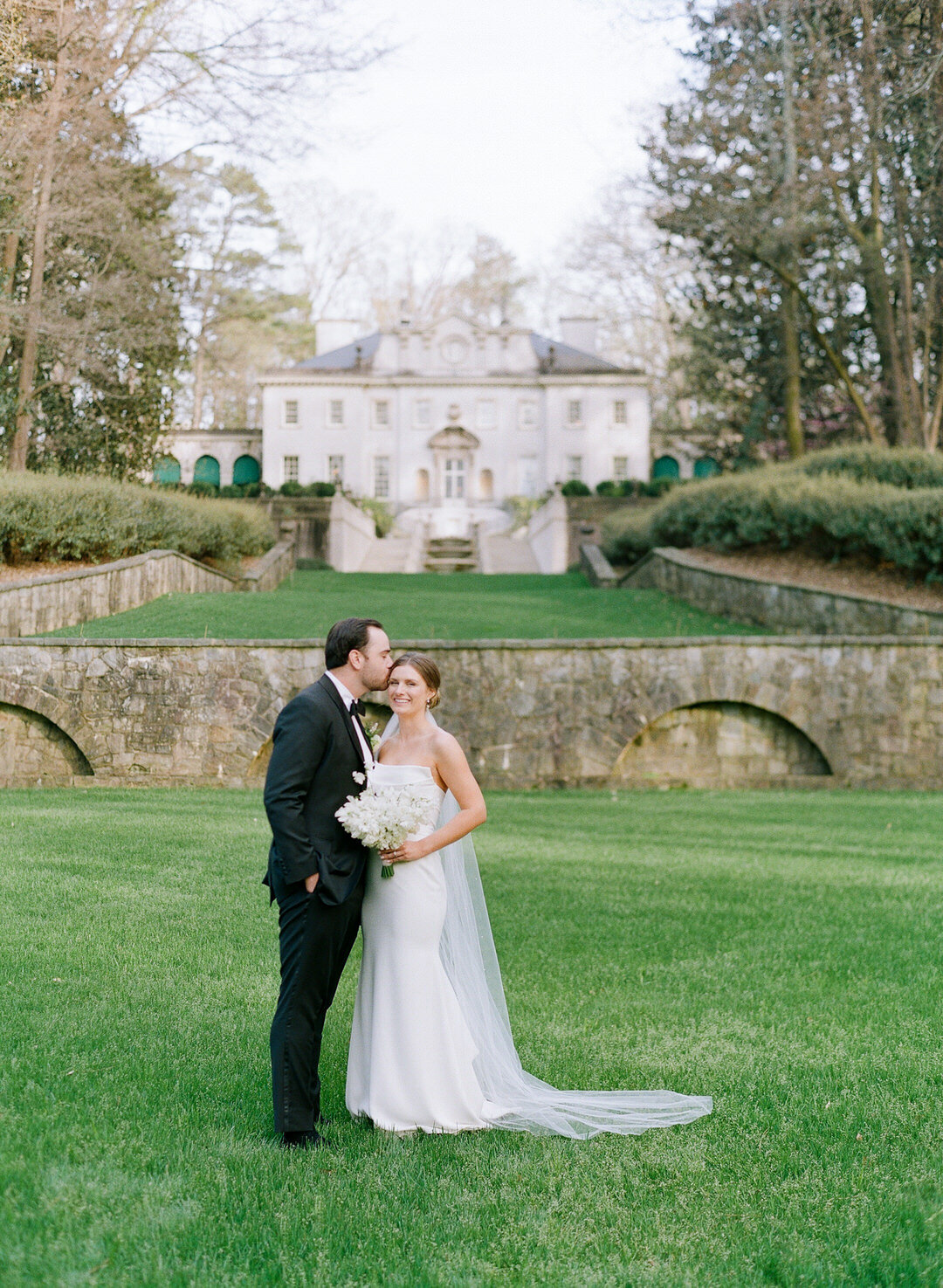 Groom Kissing Bride on Forehead in Front of Swan House in Atlanta