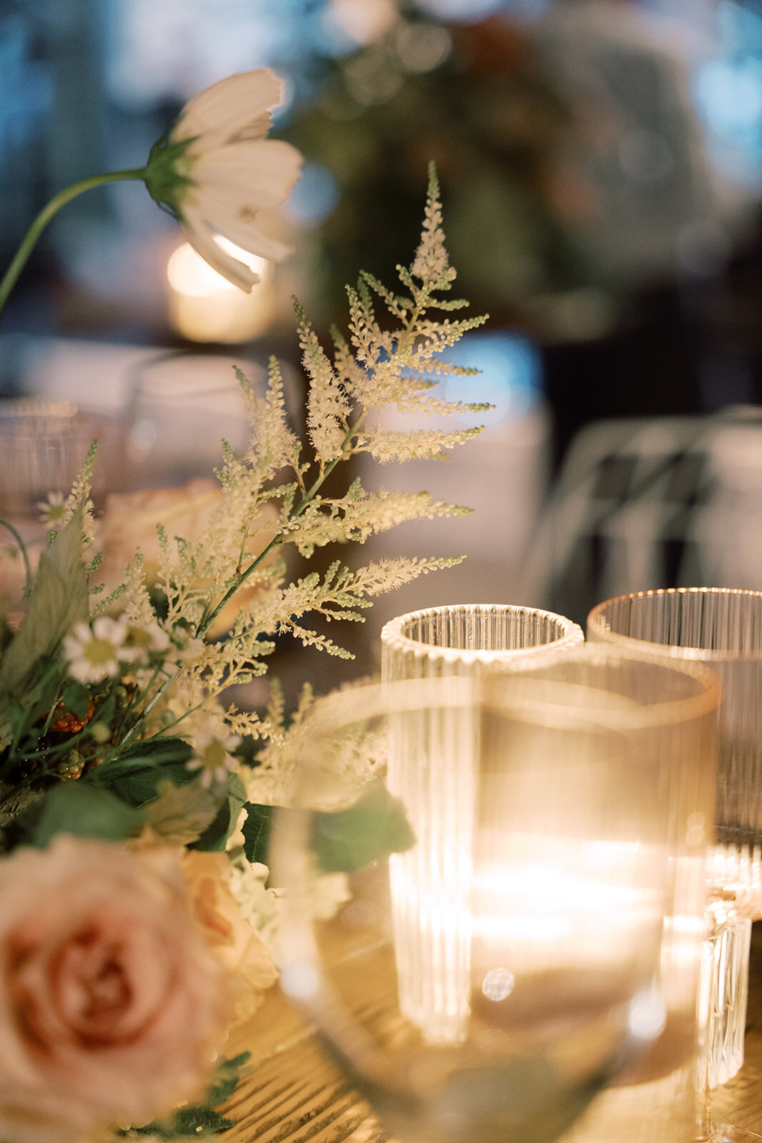 Candlelit reception besides floral arrangement including white astilbe.