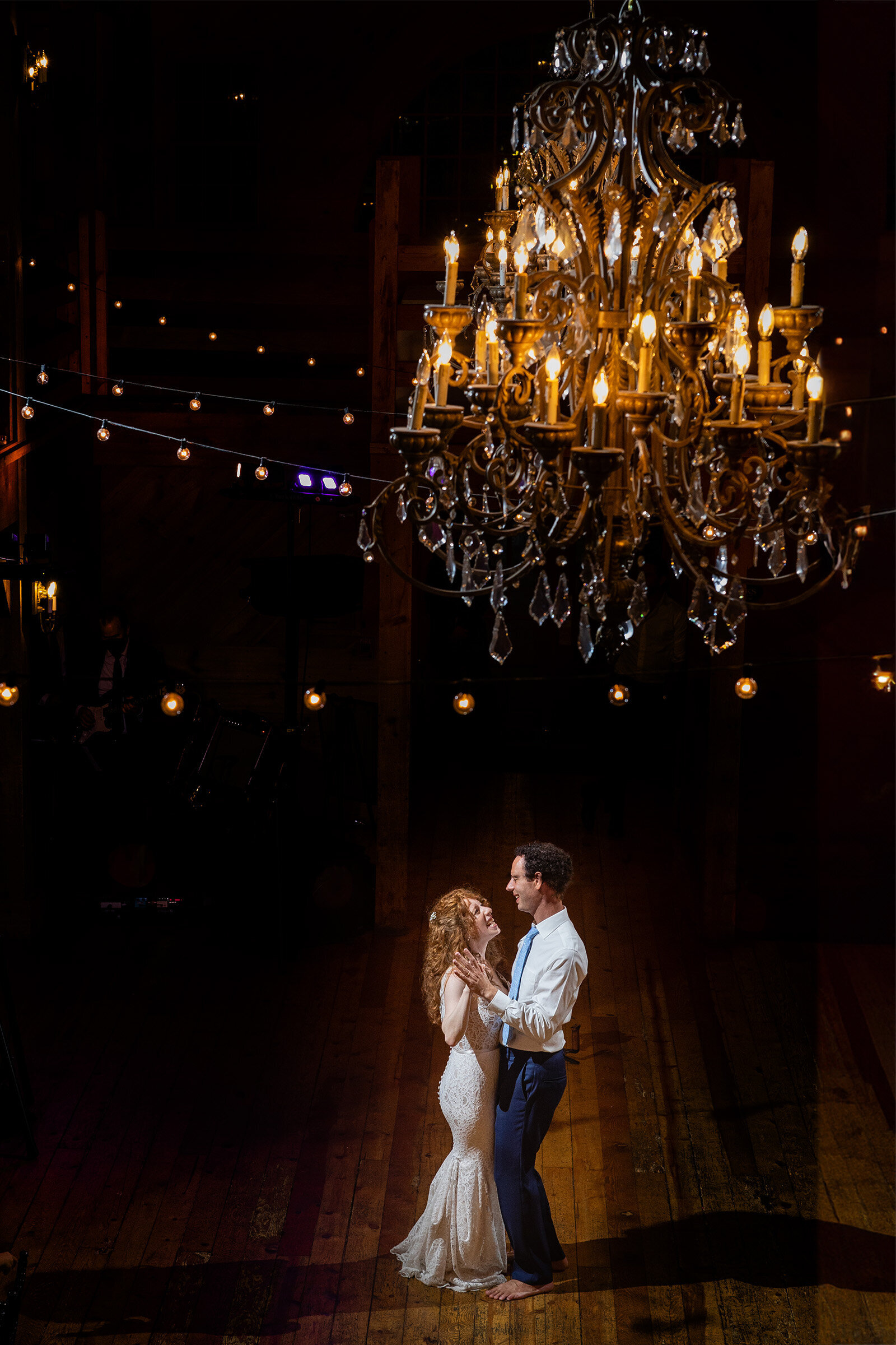 couple dances barefoot at wedding under chandelier